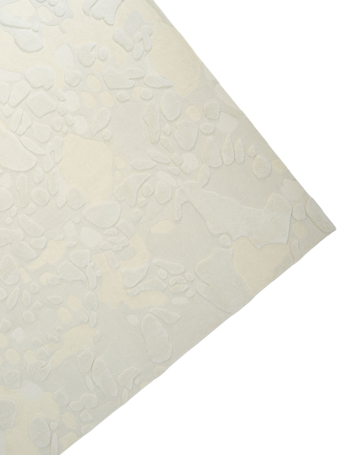 A close-up of the corner of the Creative Multi Color Wool & Cotton Handmade Rug - HTW 69 (200x300cm) by RAMSHA HOME showcases its neutral tones and subtle, irregular abstract pattern reminiscent of scattered pebbles or organic shapes, expertly crafted with hand-tufted wool and cotton.