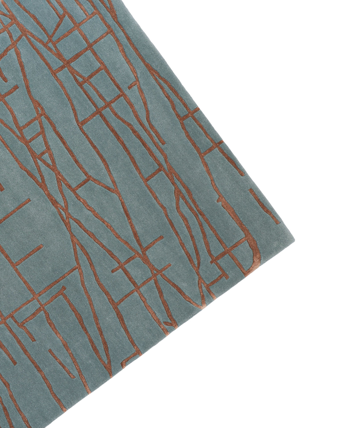 A close-up of the RAMSHA HOME Abstract Rust Line Grid Teal Rug – HTWV-31 (180x270 CM), hand tufted from wool and viscose in blue-green tones, featuring an abstract grid pattern with intersecting rust lines, photographed at an angle against a white background.