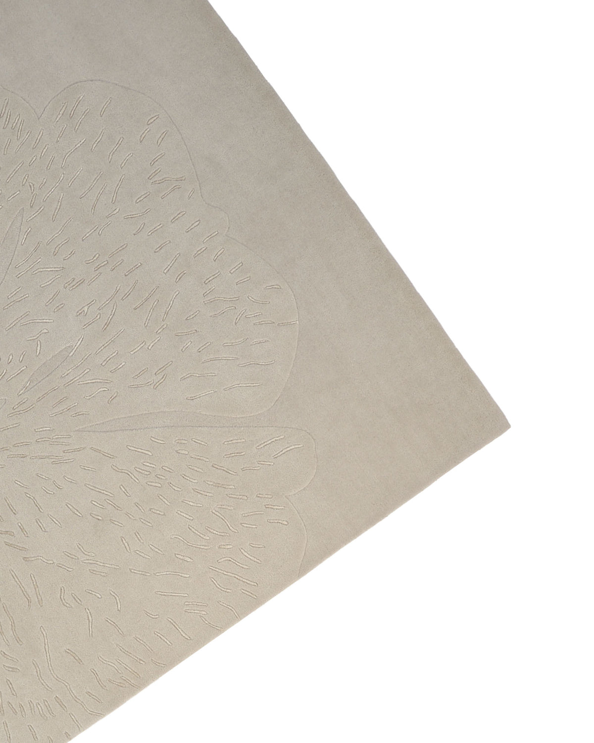A close-up of the corner of the RAMSHA HOME Embossed Floral Solid Light Grey Rug – HTWV 171 reveals its subtle, abstract textured pattern. The hand-tufted design features raised lines that form organic, leaf-like shapes.