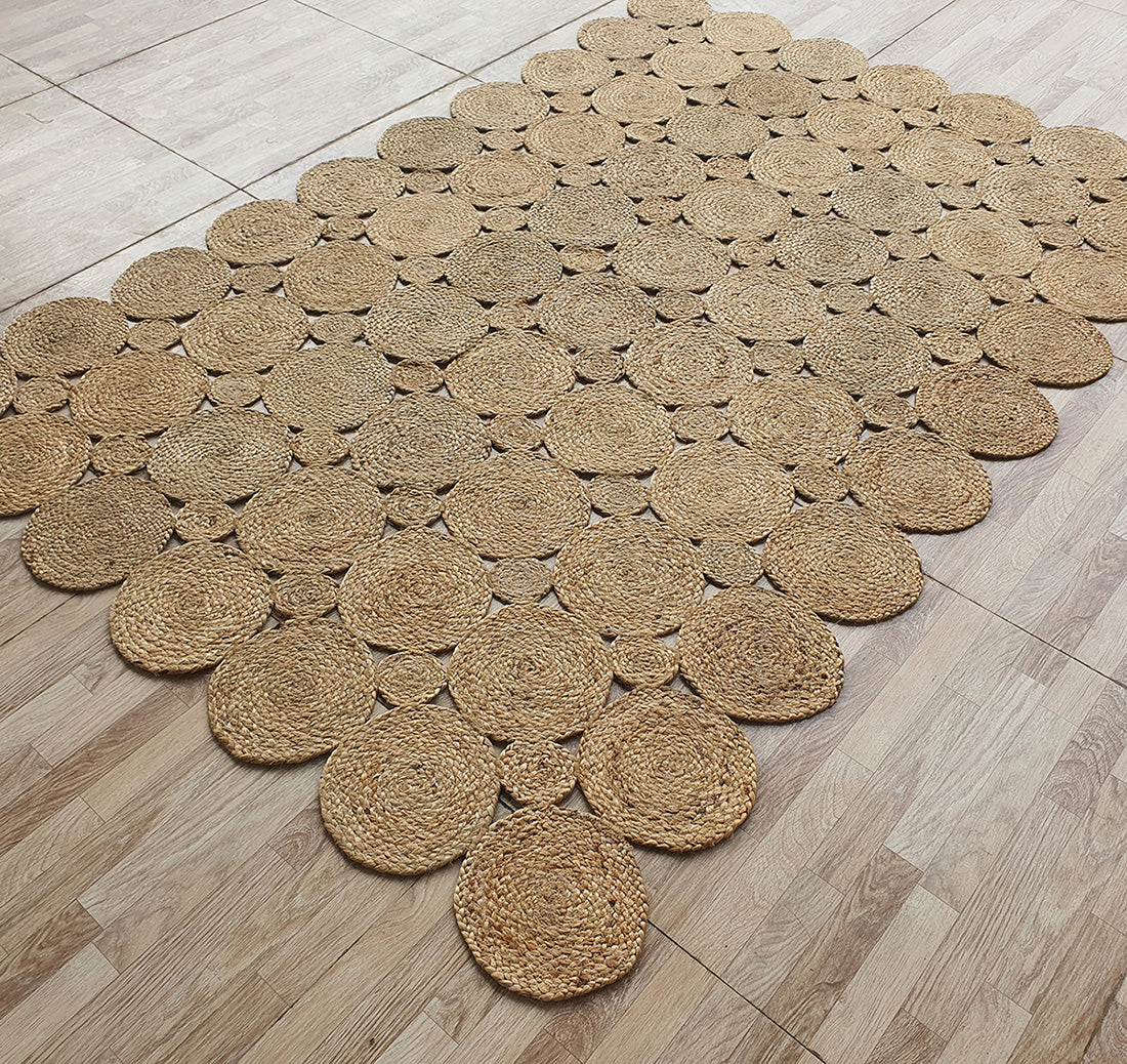 The RAMSHA HOME Handmade Circular Pattern Jute Rug BR-035 features multiple circular pieces joined for a scalloped edge design, shown here on a light wood floor.