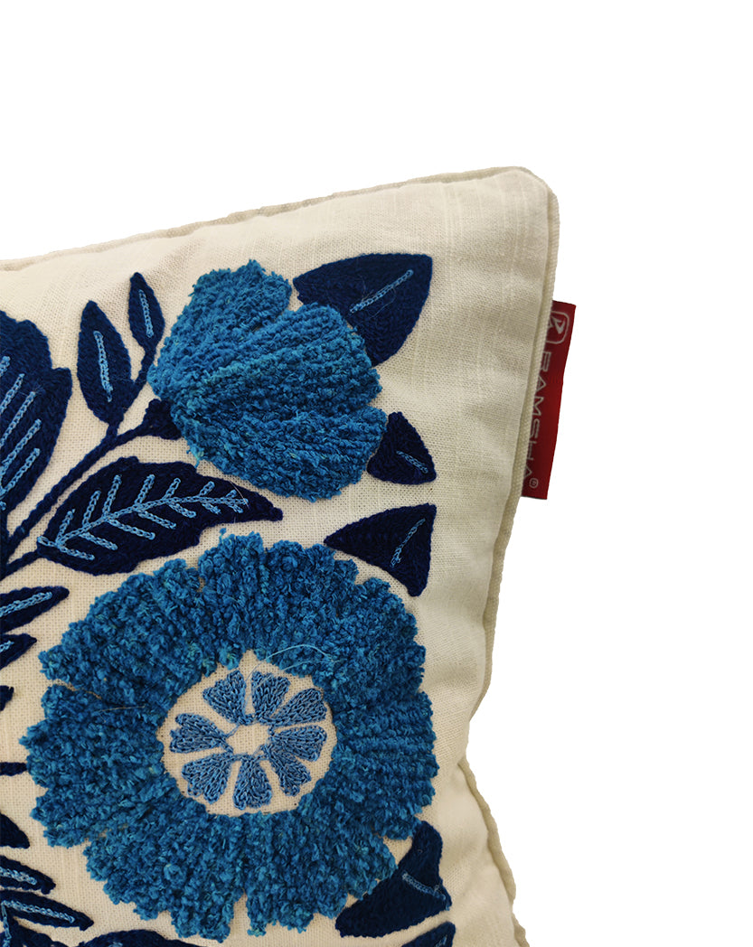 The RAMSHA HOME Blue Flower Embroidery Cushion CS-267 features a cream base with intricate blue floral embroidery and a red tag on the seam. Only one corner is shown against a white background, making it ideal for enhancing your home décor.