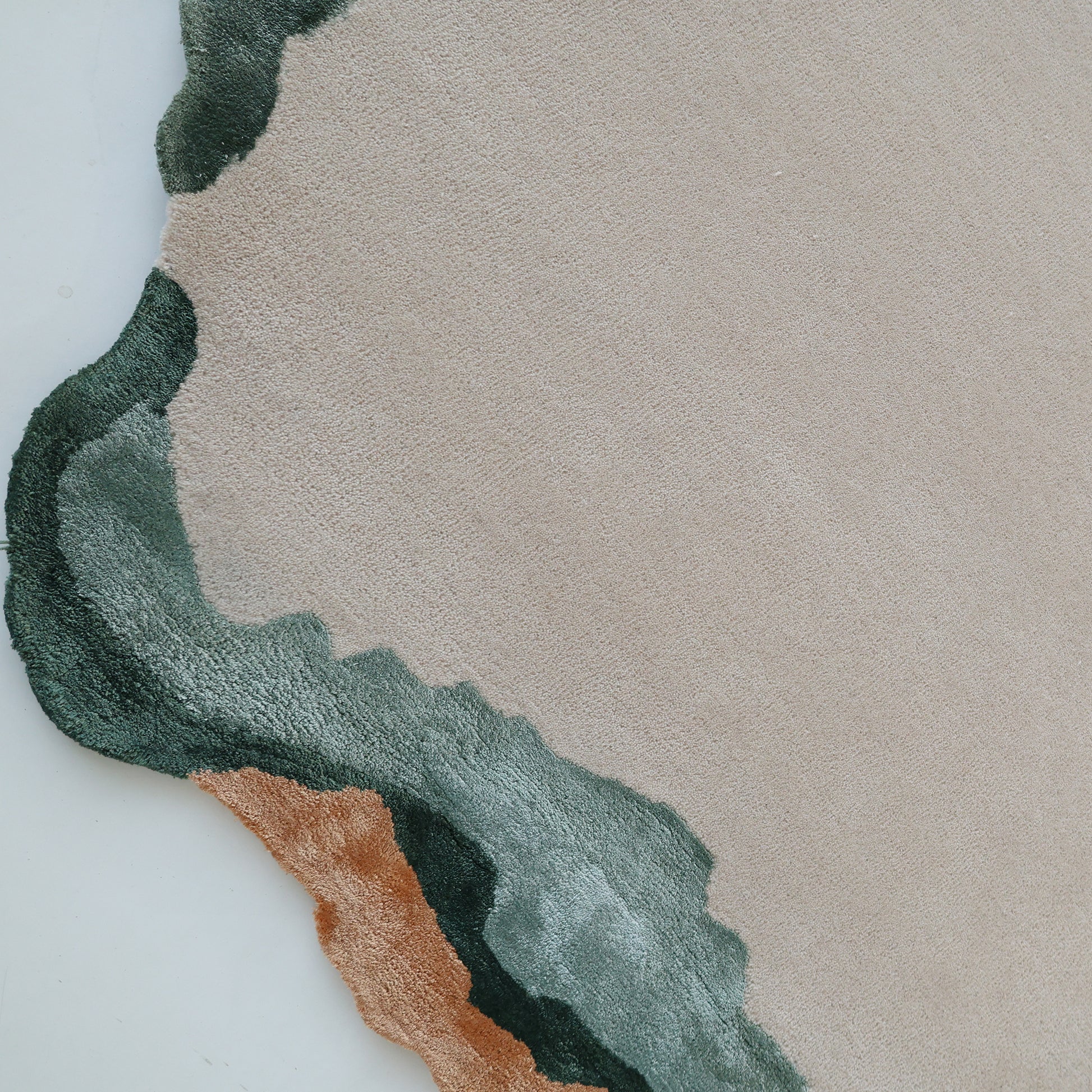 A close-up of the RAMSHA HOME Handmade Decorative Multi Color Rug HTWV-92 shows its modern wool design with an irregular, wavy green and brown edge, forming an abstract organic border.