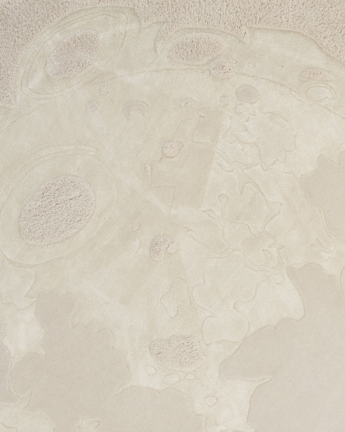 A sandy beach marked by patterns like those on the moon’s surface, with broad craters and textured areas shaped by wind or water, closely mirrors the intricate design of the Natural Color Handmade Area Rug - HTWV-150 (200 cm) from RAMSHA HOME.
