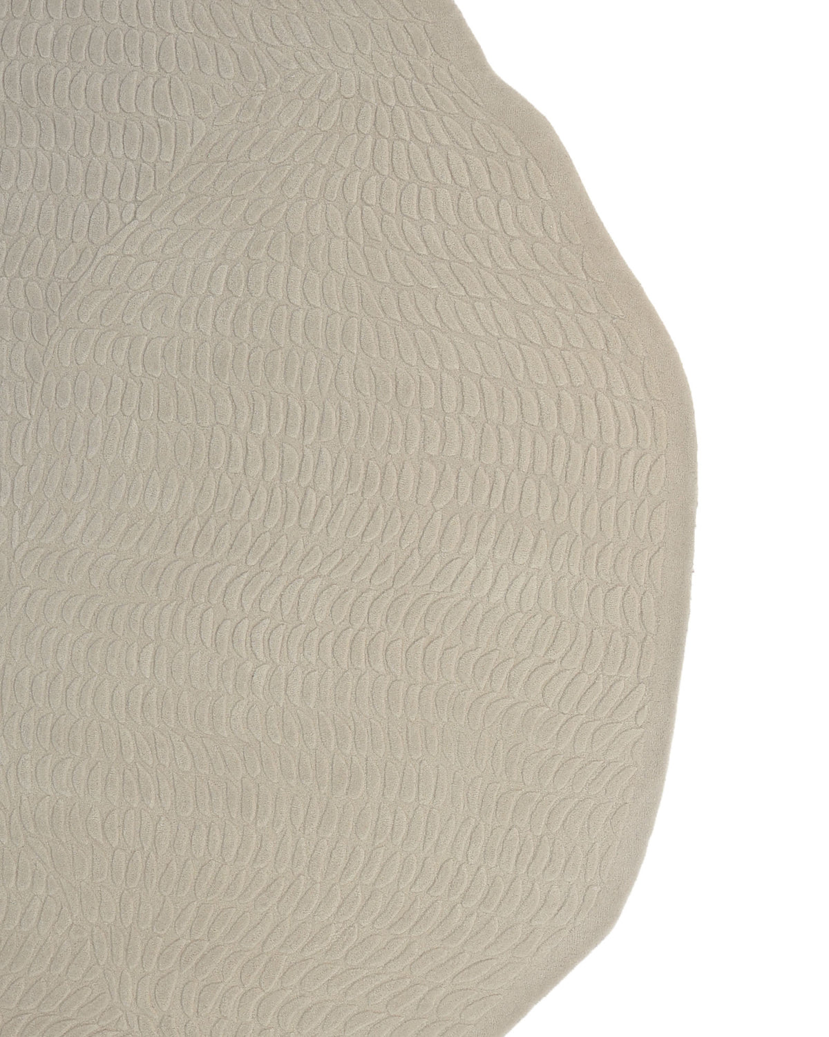 A close-up of the RAMSHA HOME Beige Color Shape Handmade Rug HTW 104 showcases its contemporary textured surface in beige, adorned with an irregular, leaf-inspired pattern. The curved edge of this hand-tufted rug stands out crisply against the white background.