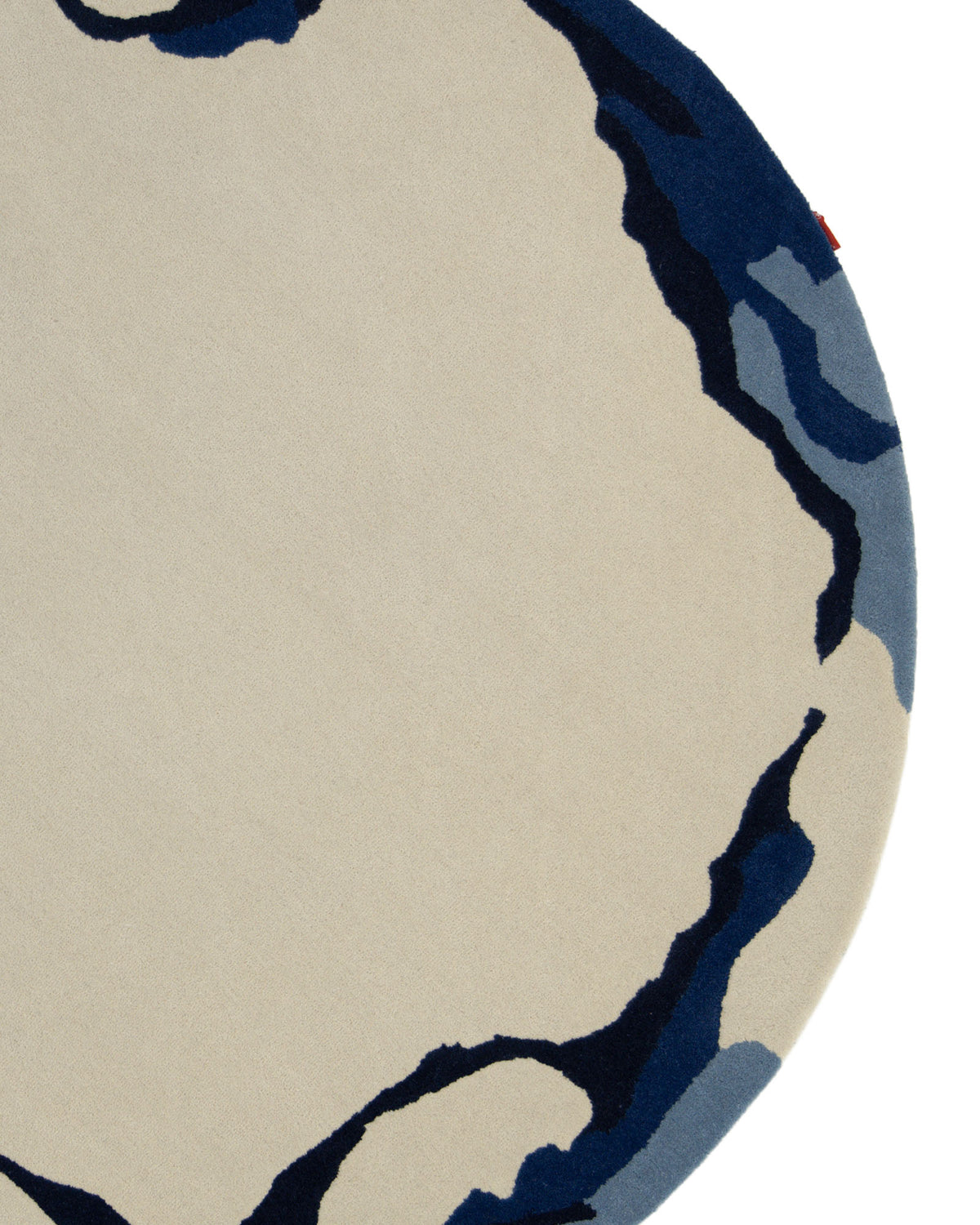 The Round Handmade Hand Tufted Carpet HTW-64 by RAMSHA HOME features a beige center with abstract, wavy navy and blue border patterns on the right side. This modern area rug showcases a minimalist, artistic interpretation of topographic lines.