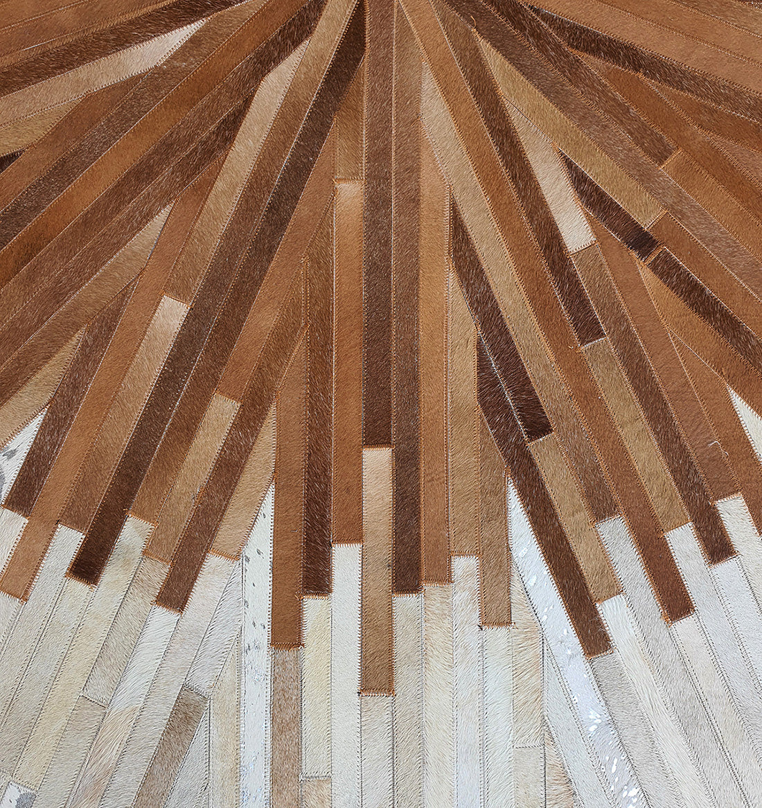 The Multi Color Round Leather Rug - LR 016 features an abstract sunburst design with wooden plank patterns in brown and beige tones, offering a modern, symmetrical, and textured look for your space.
