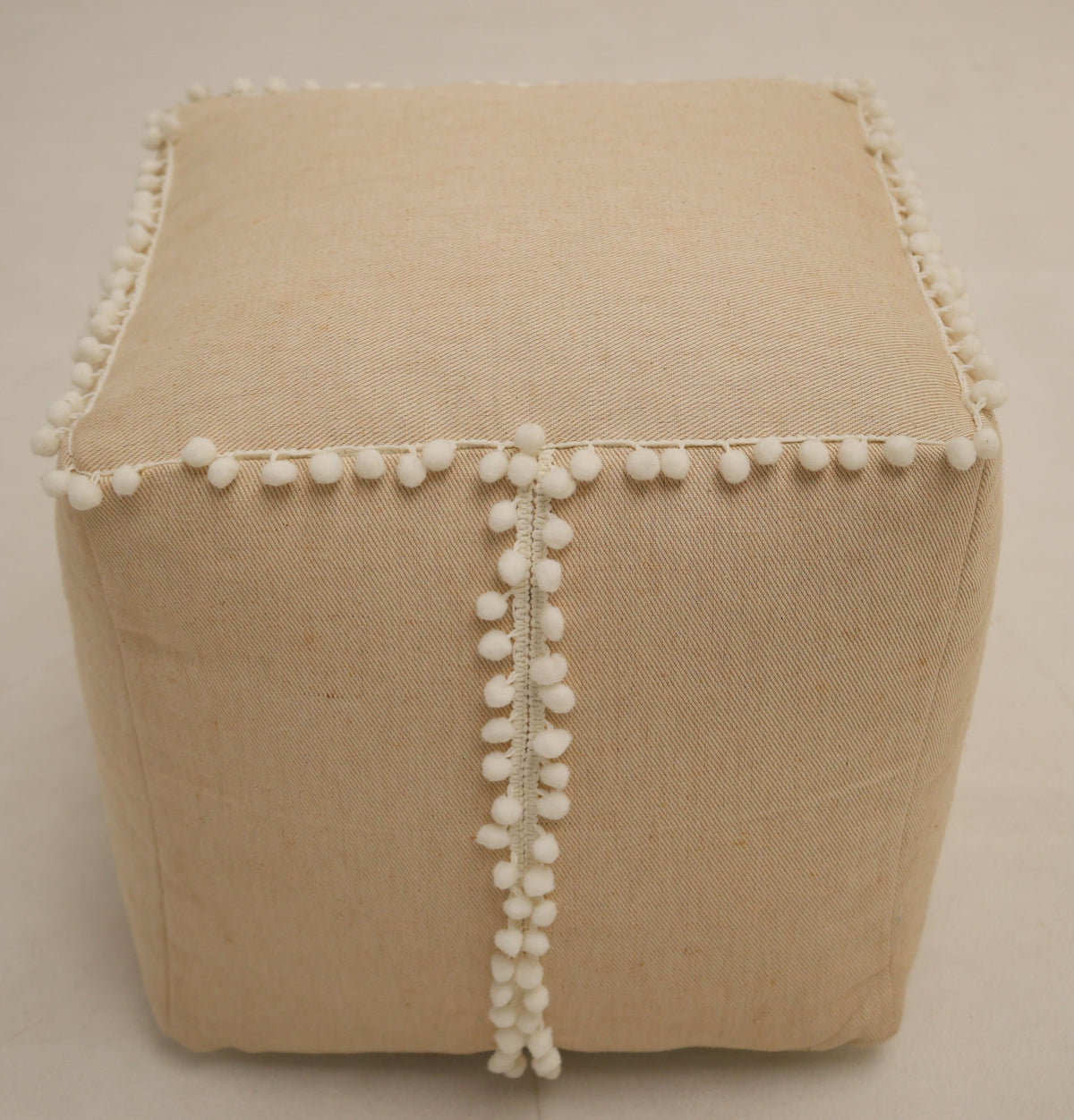 A square jute floor pouf with fringes, the RAMSHA HOME Square Jute Floor Pouf PF 193 serves as a charming accent piece when placed on a light-colored floor.