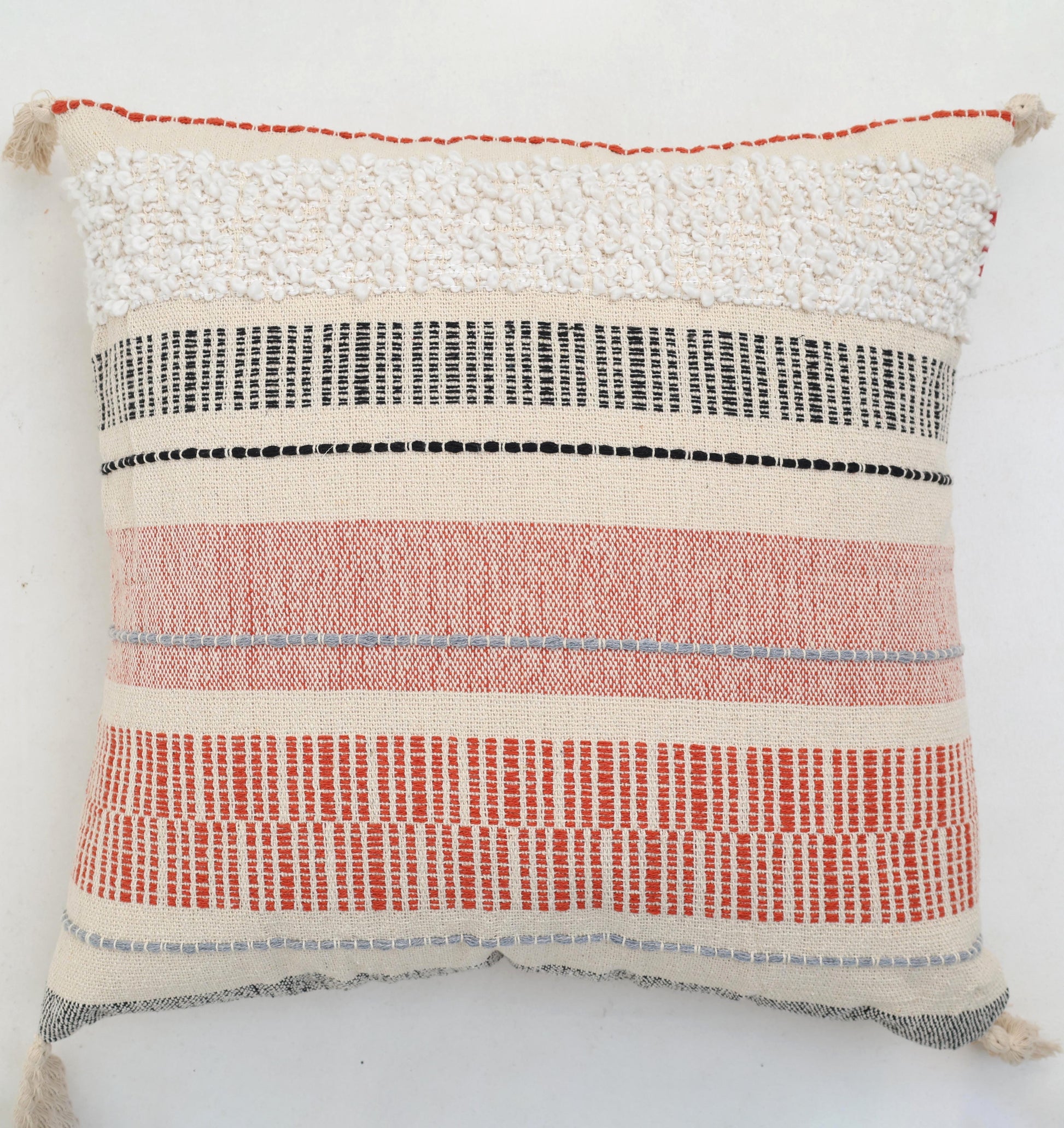 The Cream Color Home Decor Cushion - CS 314 A from Ramsha Home features textured fabric with red, black, and white stripes, a tufted fluffy top section, and woven geometric lines—perfect for stylish home interiors in the UAE.