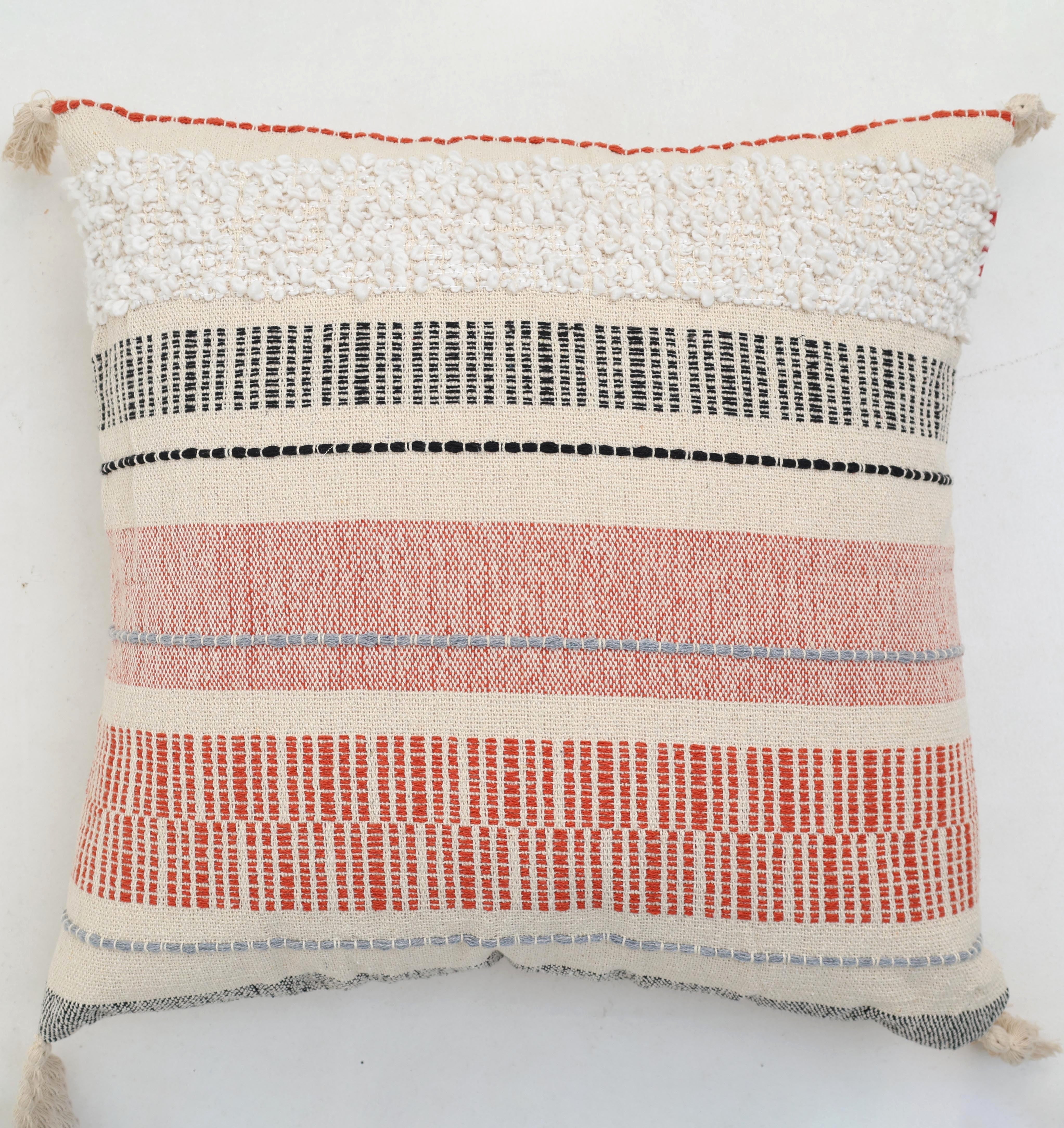 The Cream Color Home Decor Cushion - CS 314 A from Ramsha Home features textured fabric with red, black, and white stripes, a tufted fluffy top section, and woven geometric lines—perfect for stylish home interiors in the UAE.