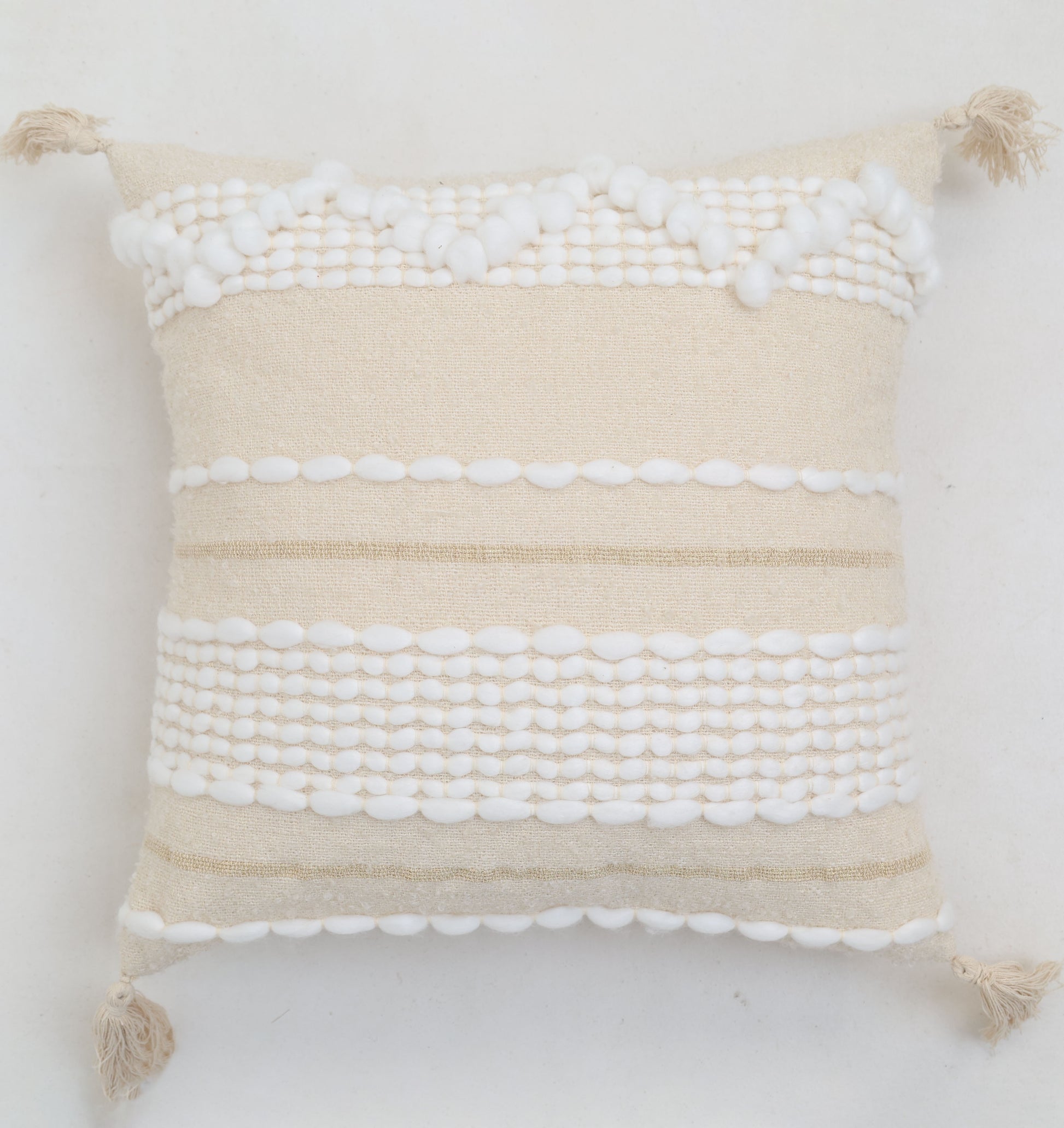 The Cream Color Home Decor Cushion - CS 313 B by Ramsha Home features textured white patterns, stripes, pom-pom details, and corner tassels for a neutral boho style—perfect for elevating your décor.
