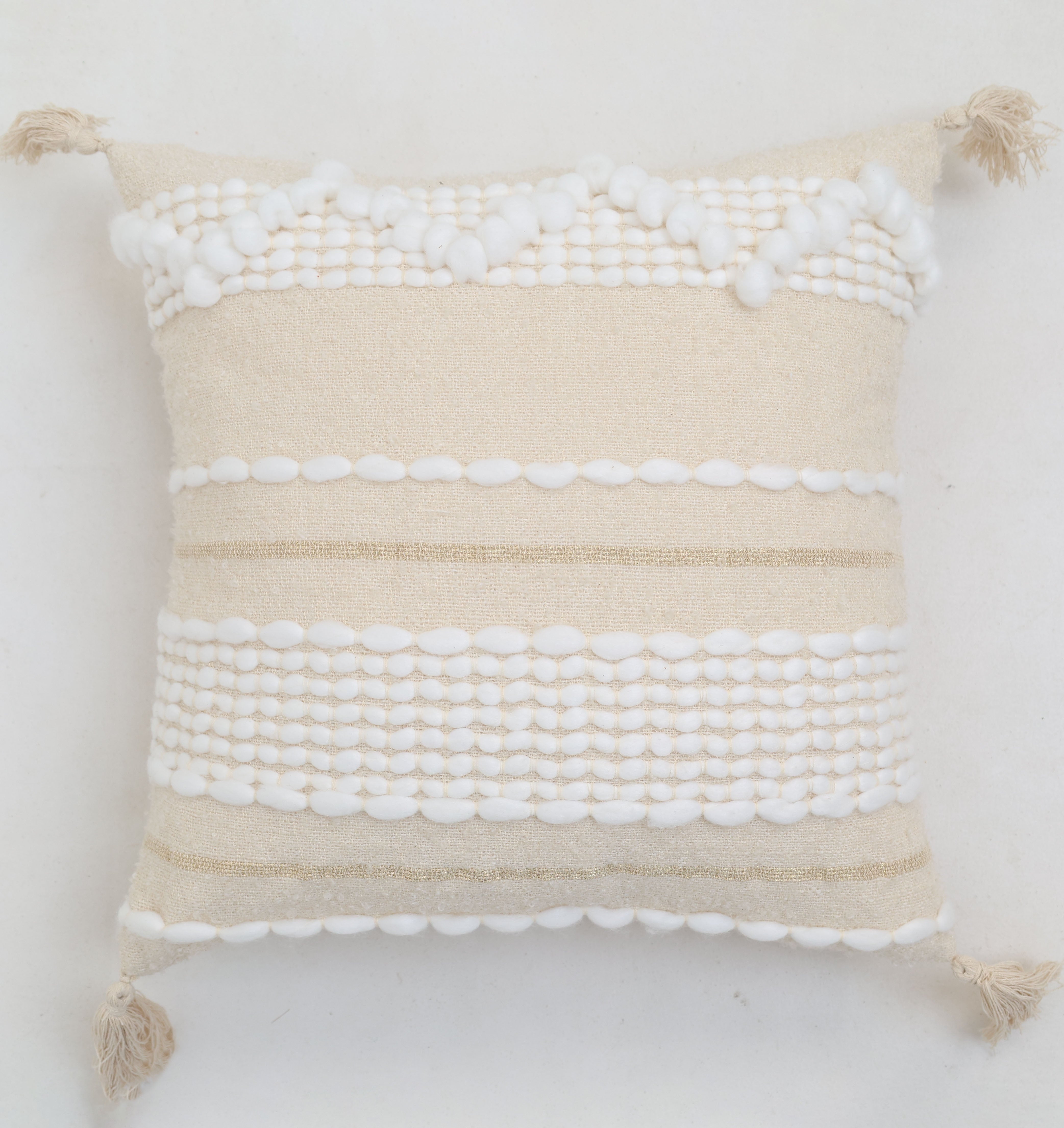 The Cream Color Home Decor Cushion - CS 313 B by Ramsha Home features textured white patterns, stripes, pom-pom details, and corner tassels for a neutral boho style—perfect for elevating your décor.