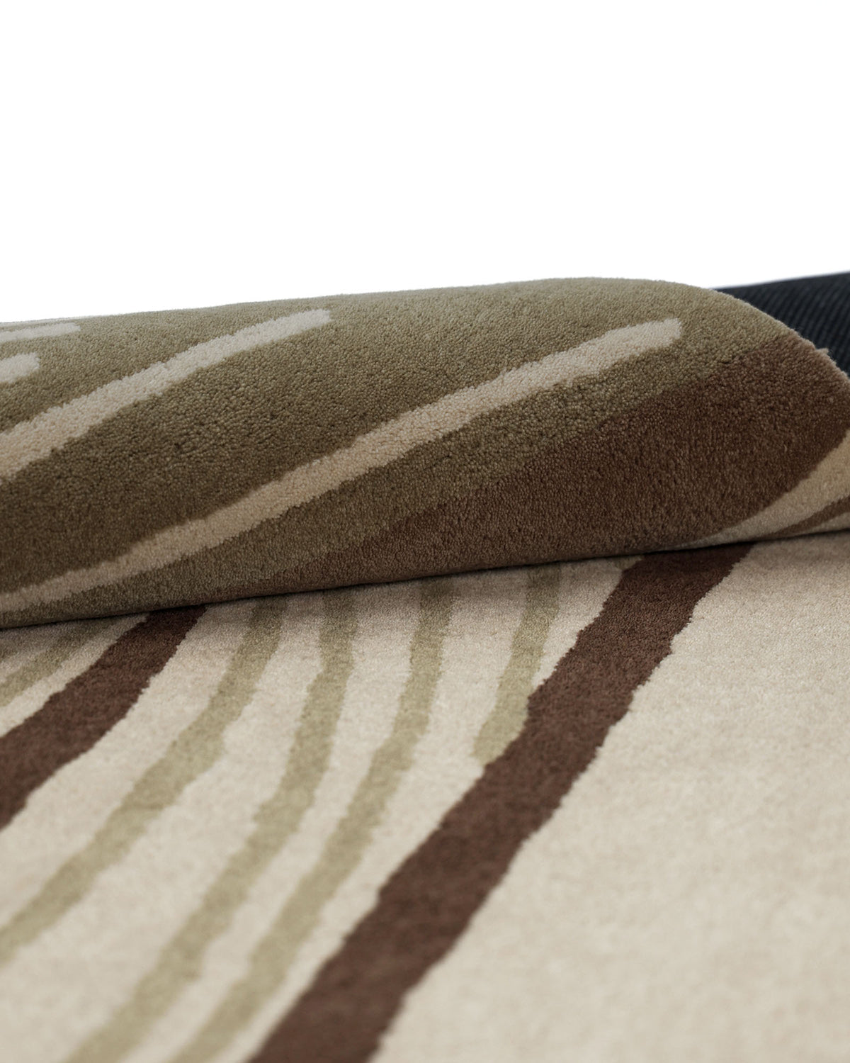 A close-up of the Striking Pattern Home Decor Handmade Carpet – HTW-61 by RAMSHA HOME, featuring a partially rolled-up modern abstract design with a beige background and brown and tan wavy stripe patterns.