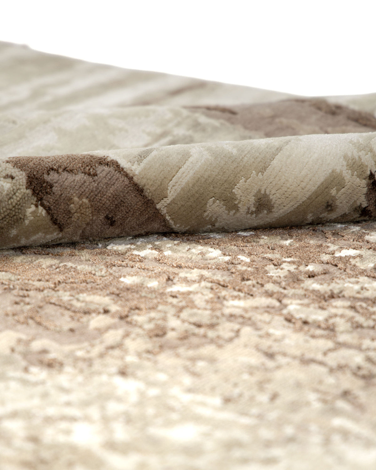 A close-up of the RAMSHA HOME Hand-Knotted Woodland Bamboo Silk & NZ Wool Rug (HKWB-04, 240x300 CM) showcases its folded, textured surface with a beige and brown abstract pattern inspired by woodland pathways. The rug appears soft and plush, featuring a slightly raised texture.
