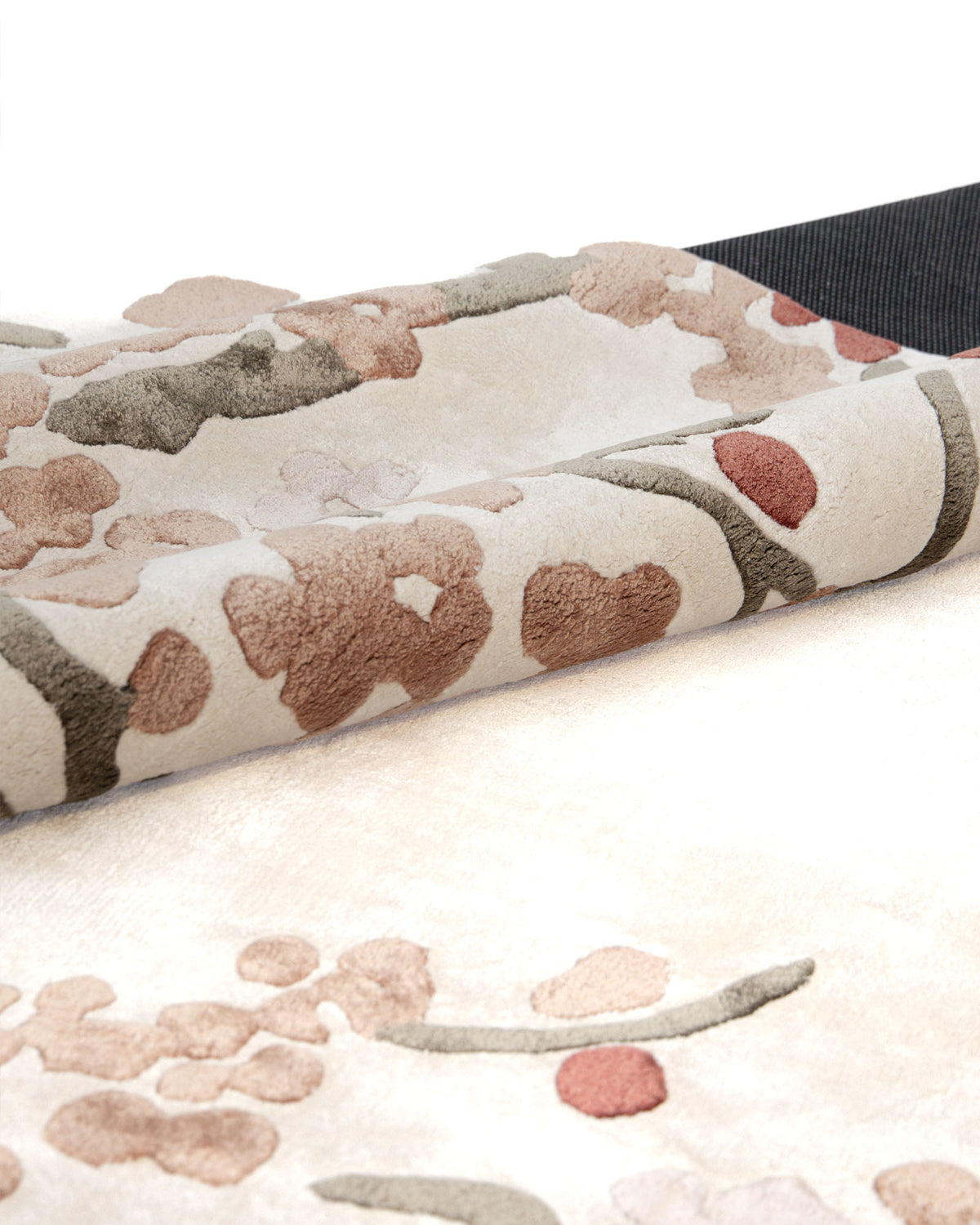 A close-up of the RAMSHA HOME Floral Blossom Area Rug – Beige Pink & Terracotta 300x400 CM- HTV-30 showcases its cream-colored surface with a raised floral pattern in pink, green, and beige tones, partially folded to reveal the textured design and underside.