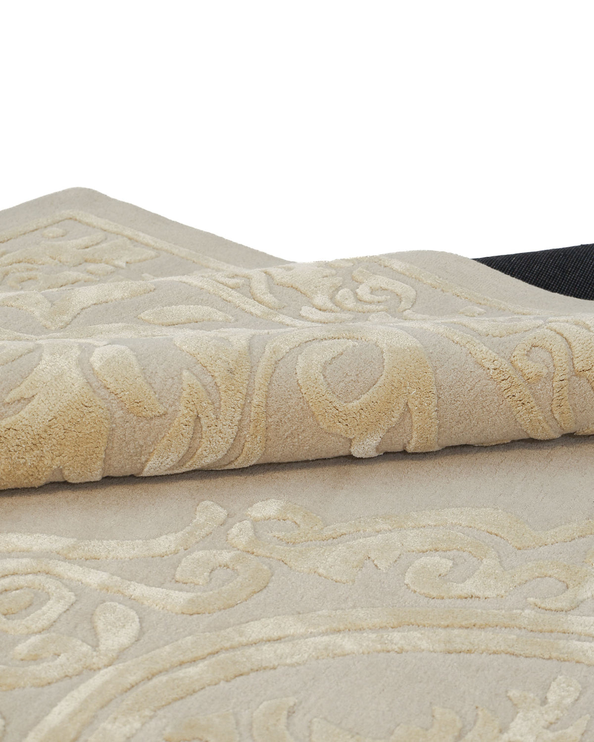 A close-up of the RAMSHA HOME Handmade Beige Area Rug (300x400 cm, HTWV-56) showcases its raised, ornate patterns. The corner of this traditional piece is folded over, emphasizing its intricate texture and detailed craftsmanship.