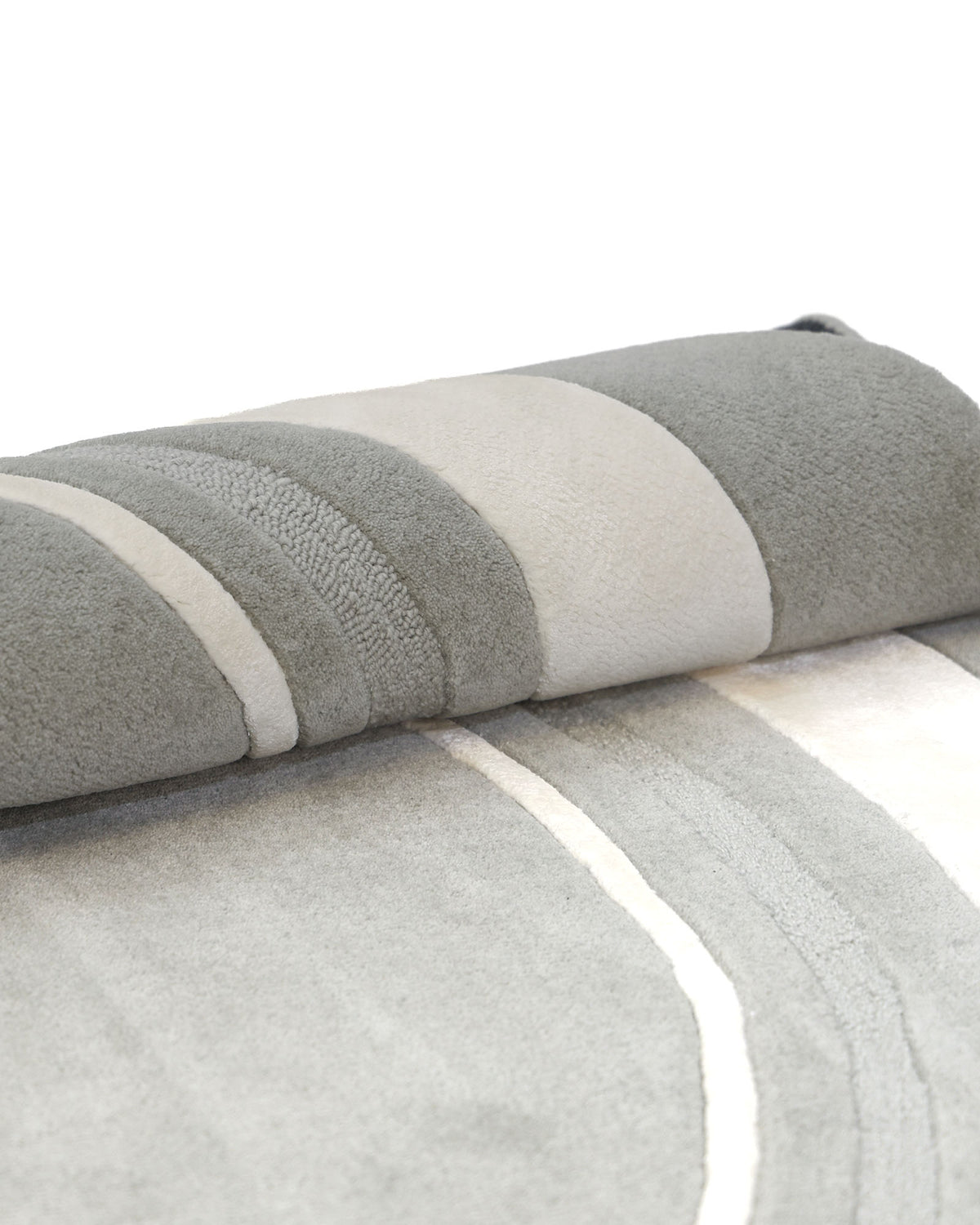 A close-up of the RAMSHA HOME Grey & White Color Round Handmade Rug - HTWV-121, rolled up to highlight its soft, plush texture and modern striped design, showcasing the stylish appeal of this elegant grey and white rug.