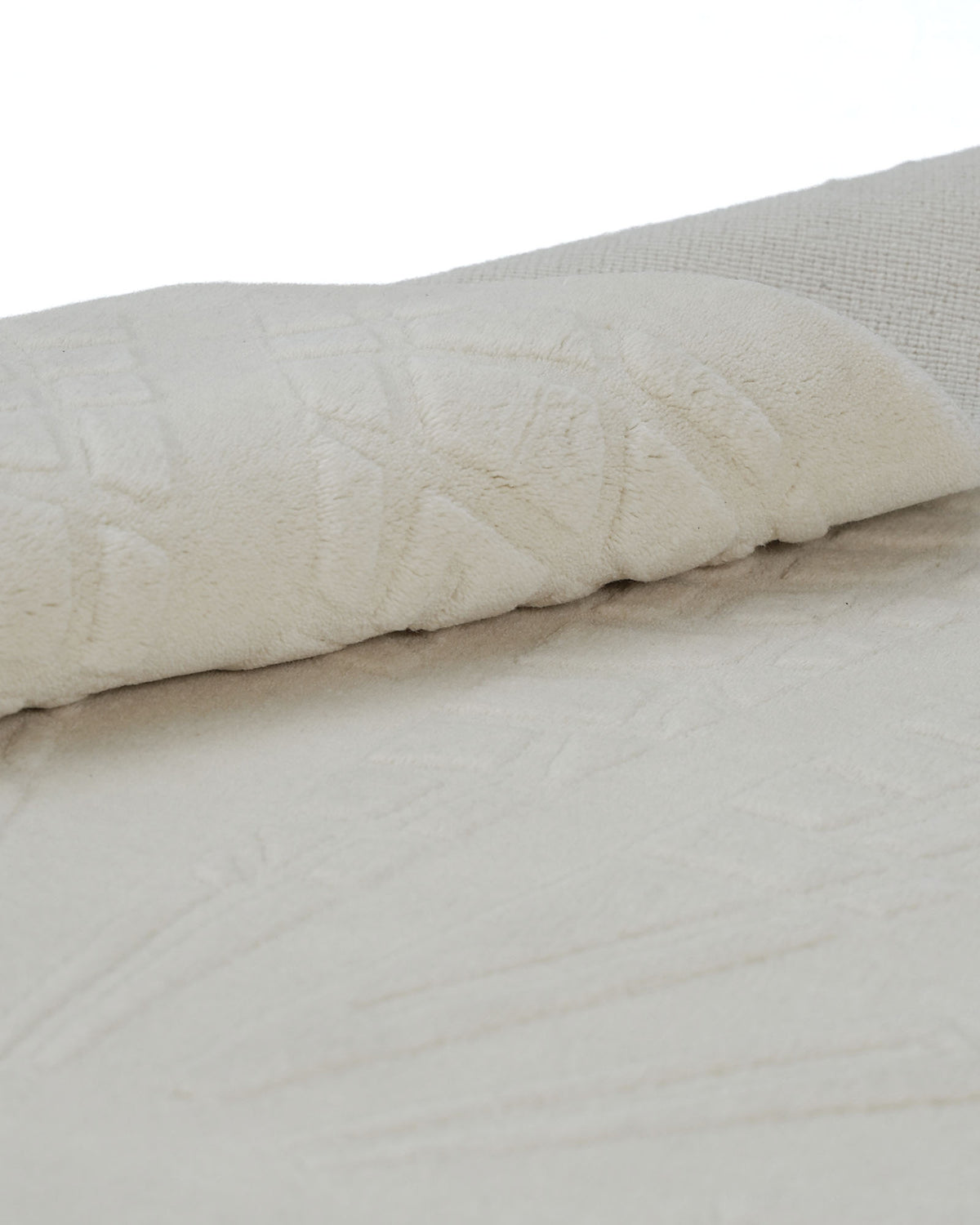 A close-up of the RAMSHA HOME Handmade Decorative Area Rug - LKH-019 (200x300 cm) in ivory, partially rolled over to display its soft, textured surface with a raised abstract pattern.