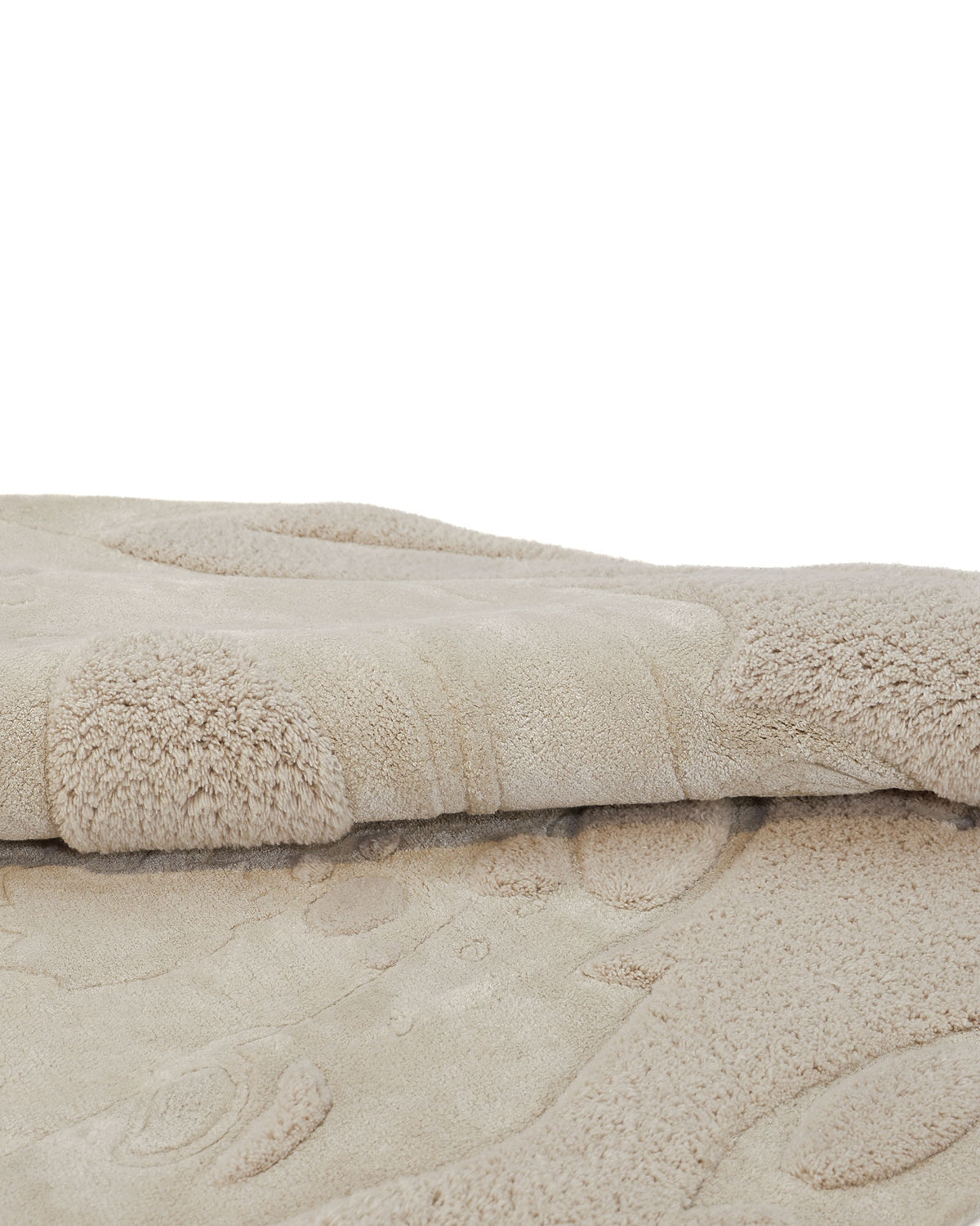 A close-up of two stacked, beige, textured bath mats with raised, wavy patterns and plush surfaces evokes the cozy feel of the RAMSHA HOME Natural Color Handmade Area Rug - HTWV-150 (200 cm), bringing warmth and subtle sophistication to any space.