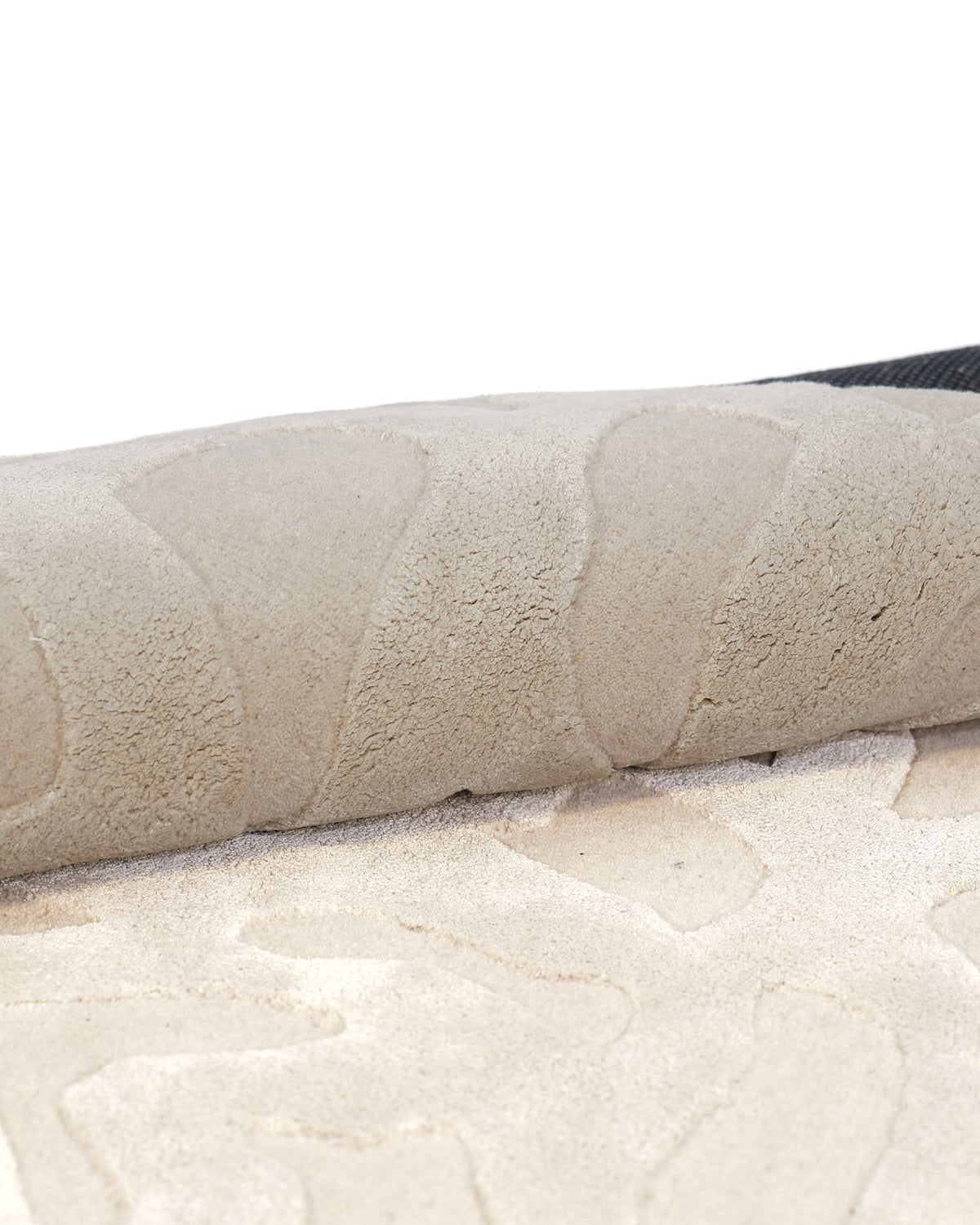 A close-up of the RAMSHA HOME Rectangle Modern Handmade Rug 200x300 CM HTWV-197 in light beige showcases its hand-woven craftsmanship with a raised, textured pattern. Partially rolled up to reveal its soft pile and finely finished underside, this elegant rug features subtle abstract designs that add dimension and sophistication to any space.