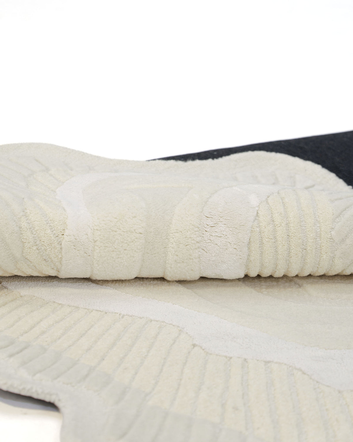 A close-up of the RAMSHA HOME Natural Handmade Area Rug (HTWV-126), showcasing its cream-colored, textured wool blend with ribbed patterns, partially rolled over a dark surface.