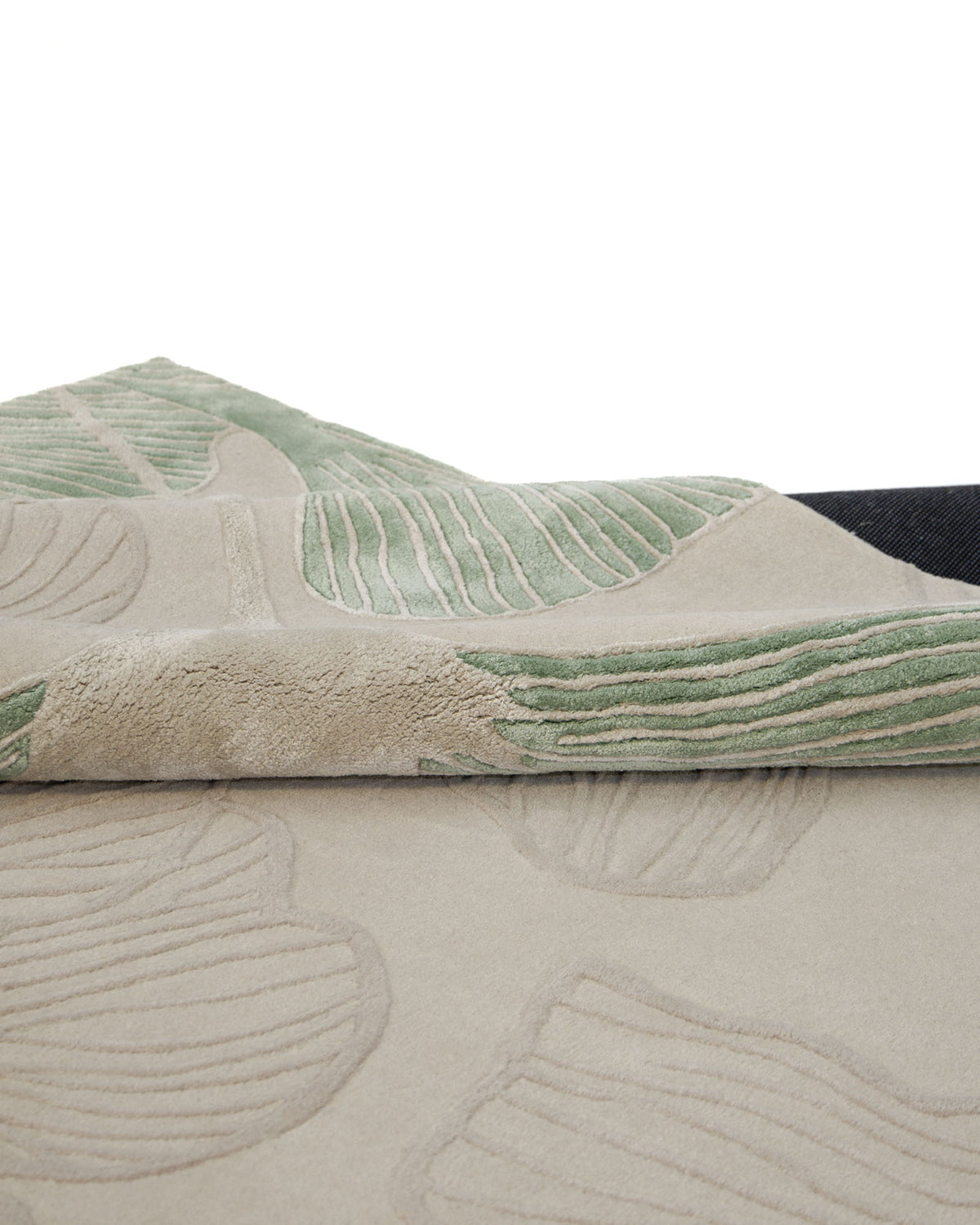 A close-up of the RAMSHA HOME Floral Handmade Rectangle Rug HTWV-189 highlights its plush beige texture with green and beige abstract leaf patterns, while a slightly lifted edge reveals the rug’s underside.