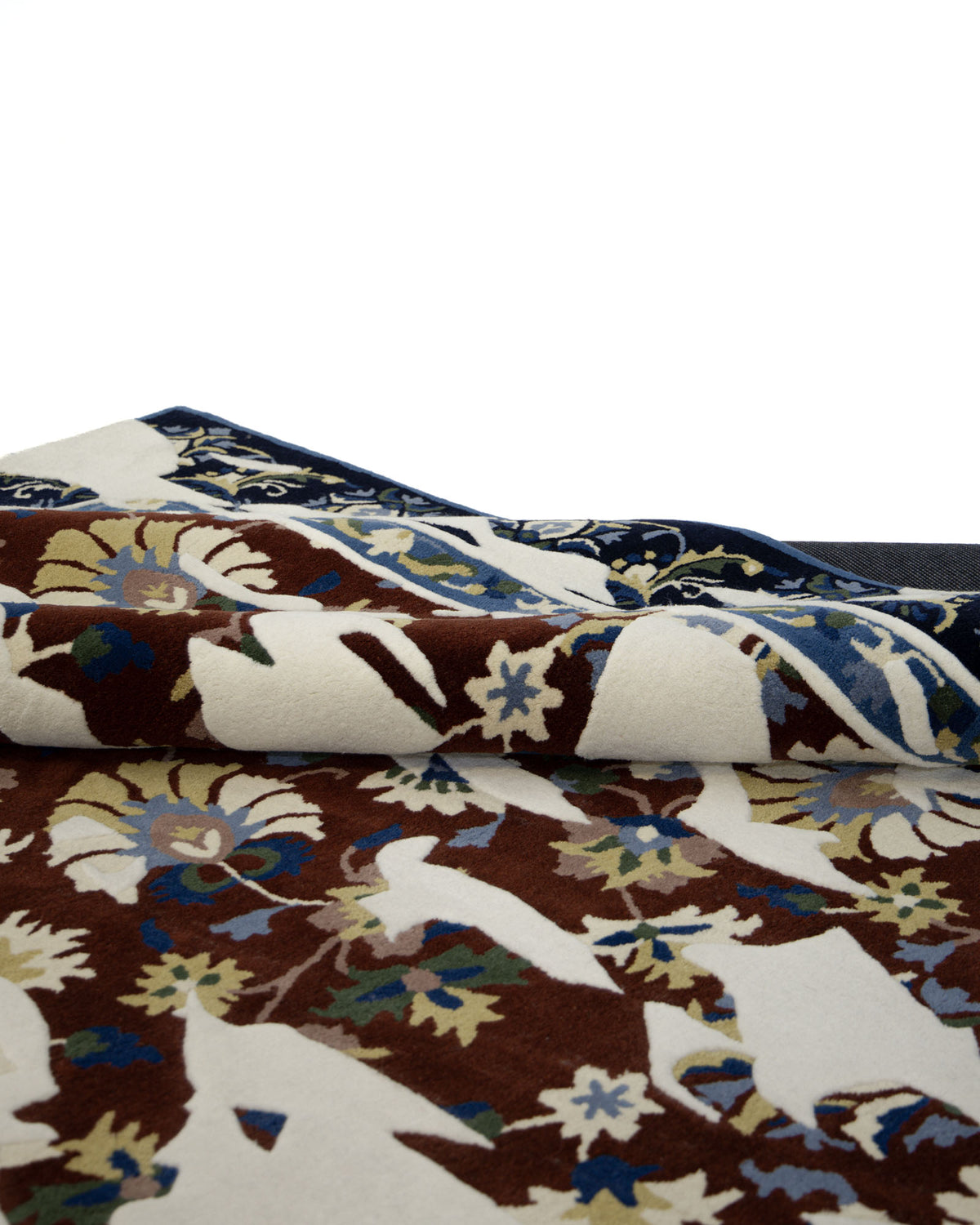 A close-up of the RAMSHA HOME Multi Color Handmade Area Rug - HTW 111 (300X400 cm), showcasing intricate floral and animal motifs in brown, white, cream, blue, and green tones, with one corner gently folded over.
