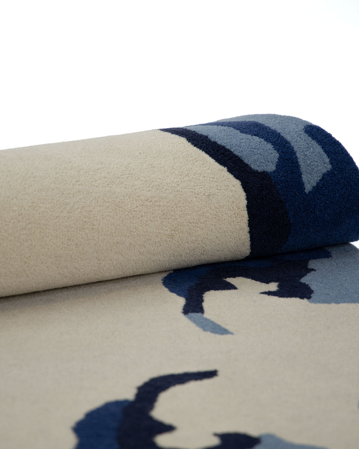 A close-up of the RAMSHA HOME Round Handmade Hand Tufted Carpet HTW-64, showcasing its abstract blue and navy patterns on a beige background, displayed against a white backdrop.