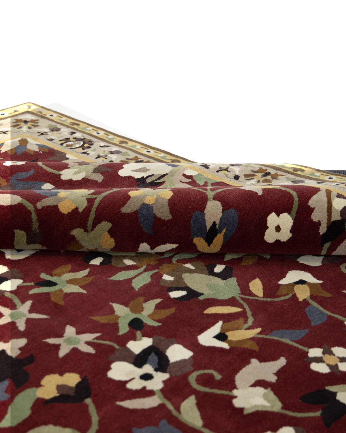A close-up of the RAMSHA HOME Wool & Cotton Handmade Area Rug HTW-08 showcases its traditional design with a maroon background, intricate multicolored floral patterns, and a folded corner that reveals a cream and gold border.
