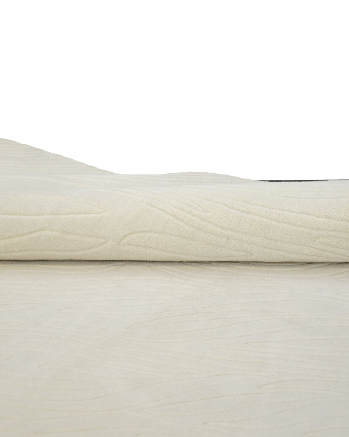 A close-up of the Natural White Color Handmade Area Rug - HTW-89 (300X400 CM) by RAMSHA HOME, showcasing its subtle textured pattern in a rolled display on a flat surface, set against a plain background that highlights its minimalist and neutral design.