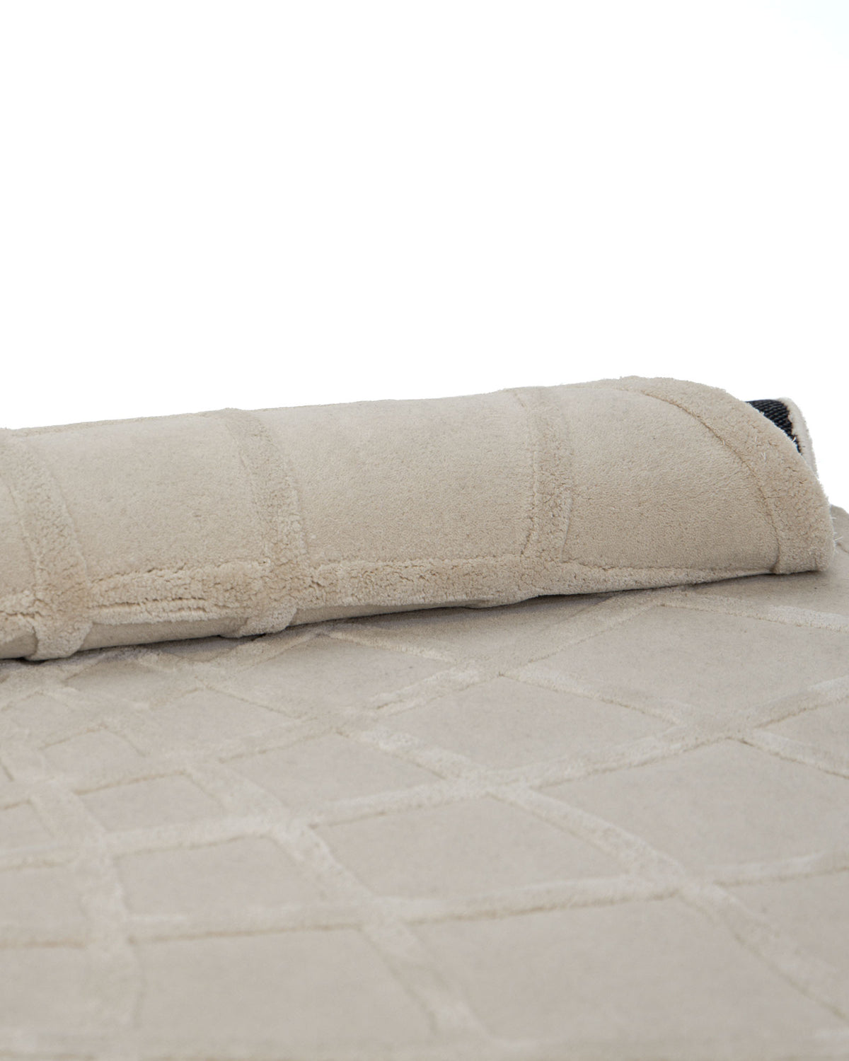 A handmade round area rug from RAMSHA HOME (HTWV 61, 200 cm), crafted from wool and viscose with a subtle geometric pattern, is partially rolled up on a white background to showcase the elegant texture of this hand-tufted piece.