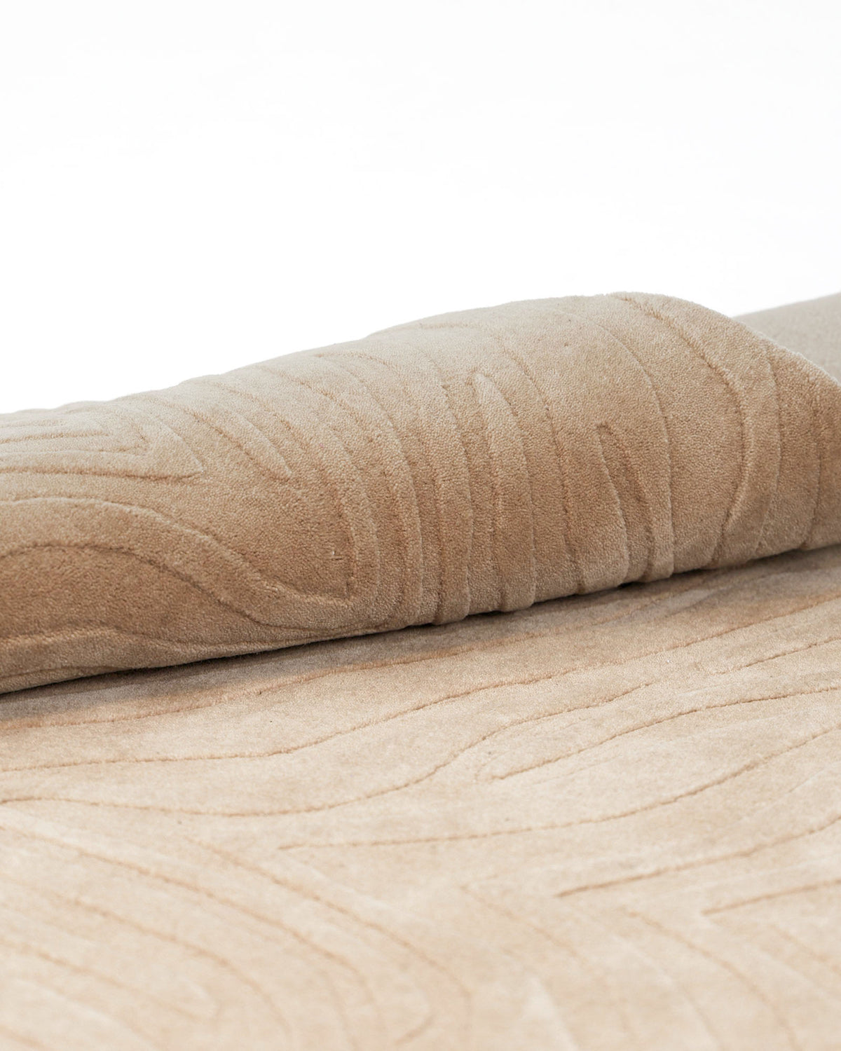 A close-up of the RAMSHA HOME Decorative Handmade Beige Color Area Rug (LKH-028), featuring raised, wavy patterns and loom-knotted detailing, partially rolled on a white background.