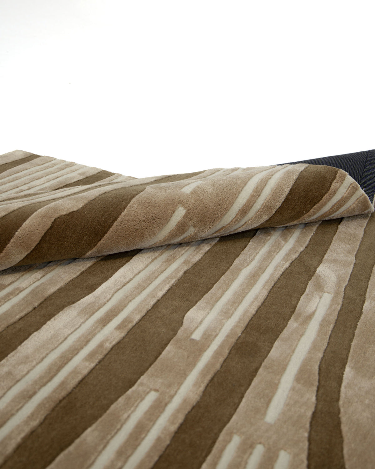 A close-up view of the RAMSHA HOME Amazing Multi Color Bedroom Floor Rug - ZUA 13 (250x350cm), showcasing its modern striped design in brown and beige, with one corner partially folded over to reveal the underside of this handtufted rug.