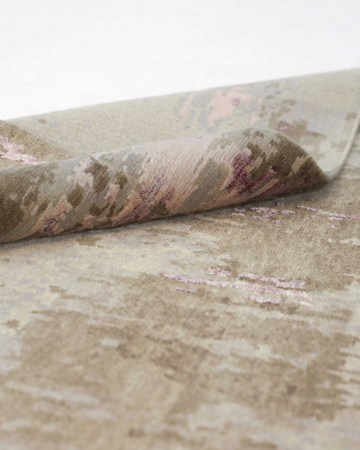 A close-up of the RAMSHA HOME Hand knotted Living Room Rug - HKWV-03 (240x300 CM) showcases its soft, beige and light purple patterned surface with one corner gently folded over, highlighting its textured feel and subtle abstract design.