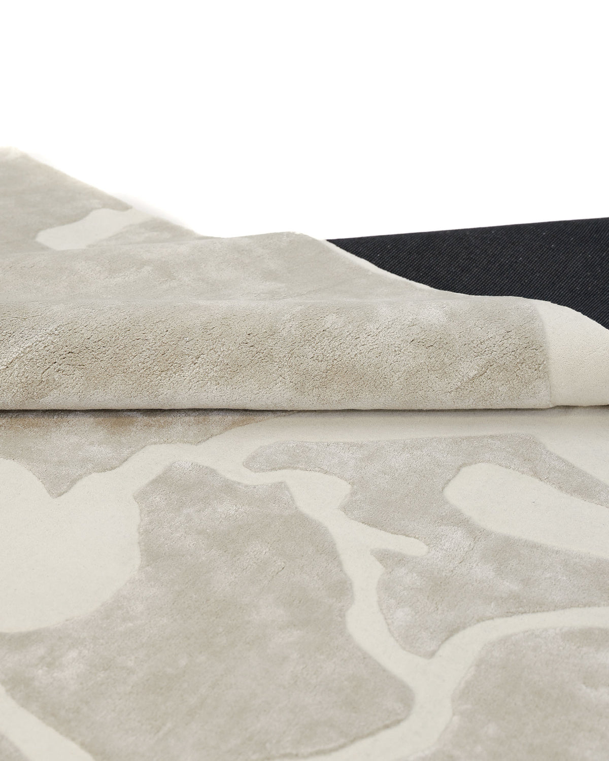 A close-up of the RAMSHA HOME Multi Color Handmade Area Rug - HTWV-132 showcases its abstract beige design in wool and viscose, with one corner gently folded over to reveal the rug’s soft texture and durable backing.