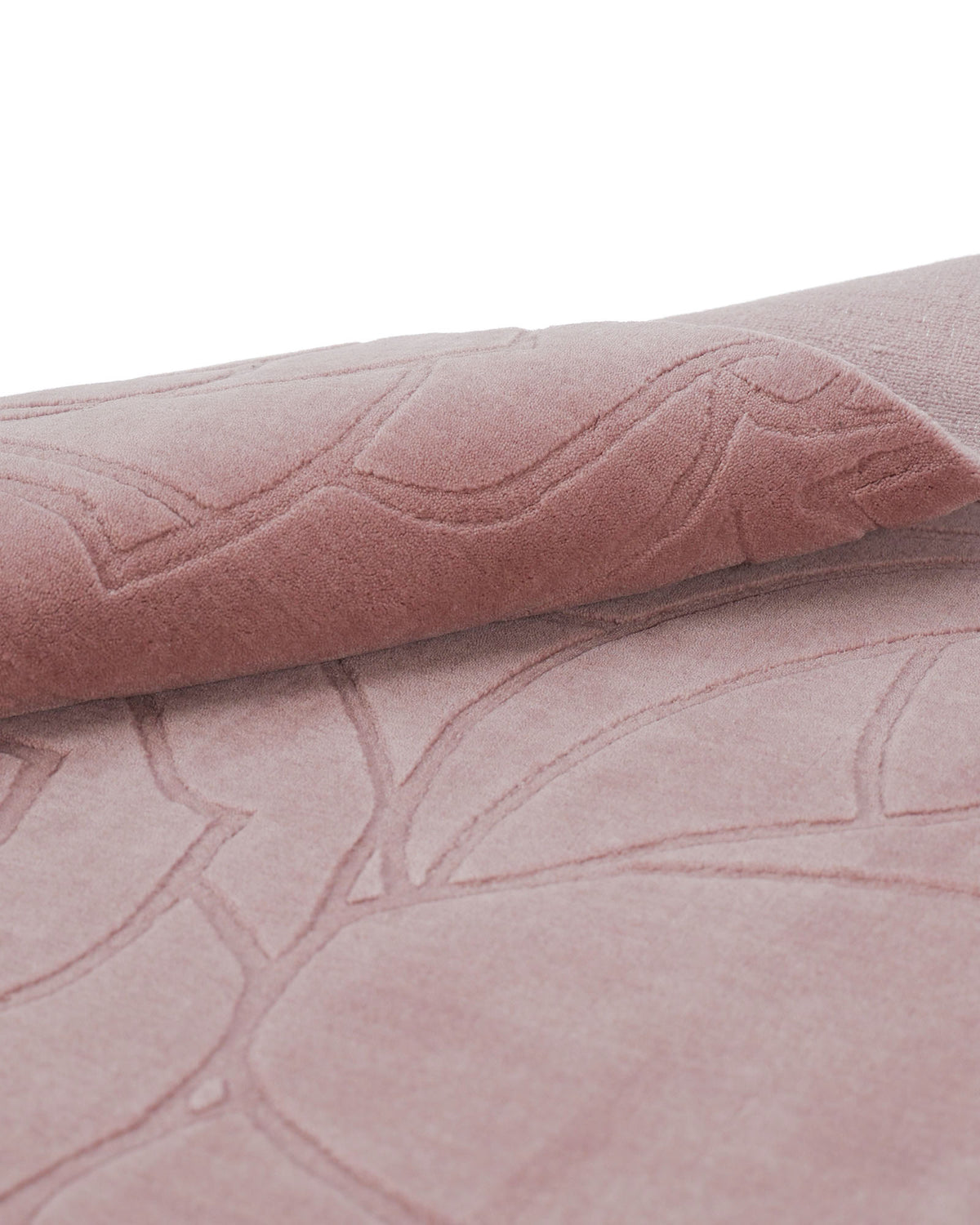 A close-up of the Rectangle Handmade Pink Color Area Rug - LKH-029 by RAMSHA HOME showcases its soft, light pink fibers and raised, stitched floral pattern, with one corner elegantly folded to reveal the intricate texture and craftsmanship.
