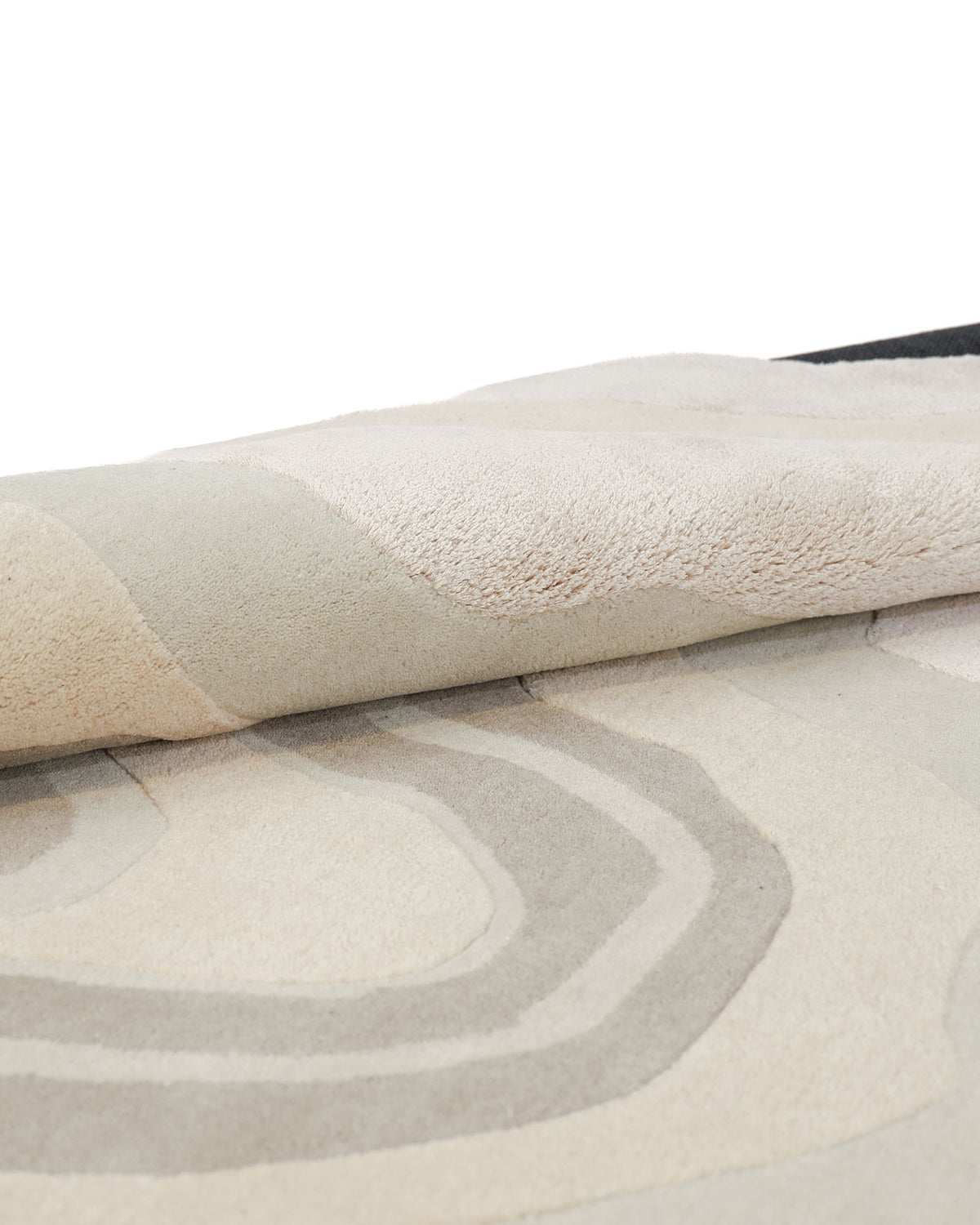 A close-up of the RAMSHA HOME Modern Spiral Shape Rug Neutral Beige & Green (200 cm – HTWV 208) reveals its wavy, layered spiral patterns in beige and green tones, with the abstract edge of the rug slightly folded over.