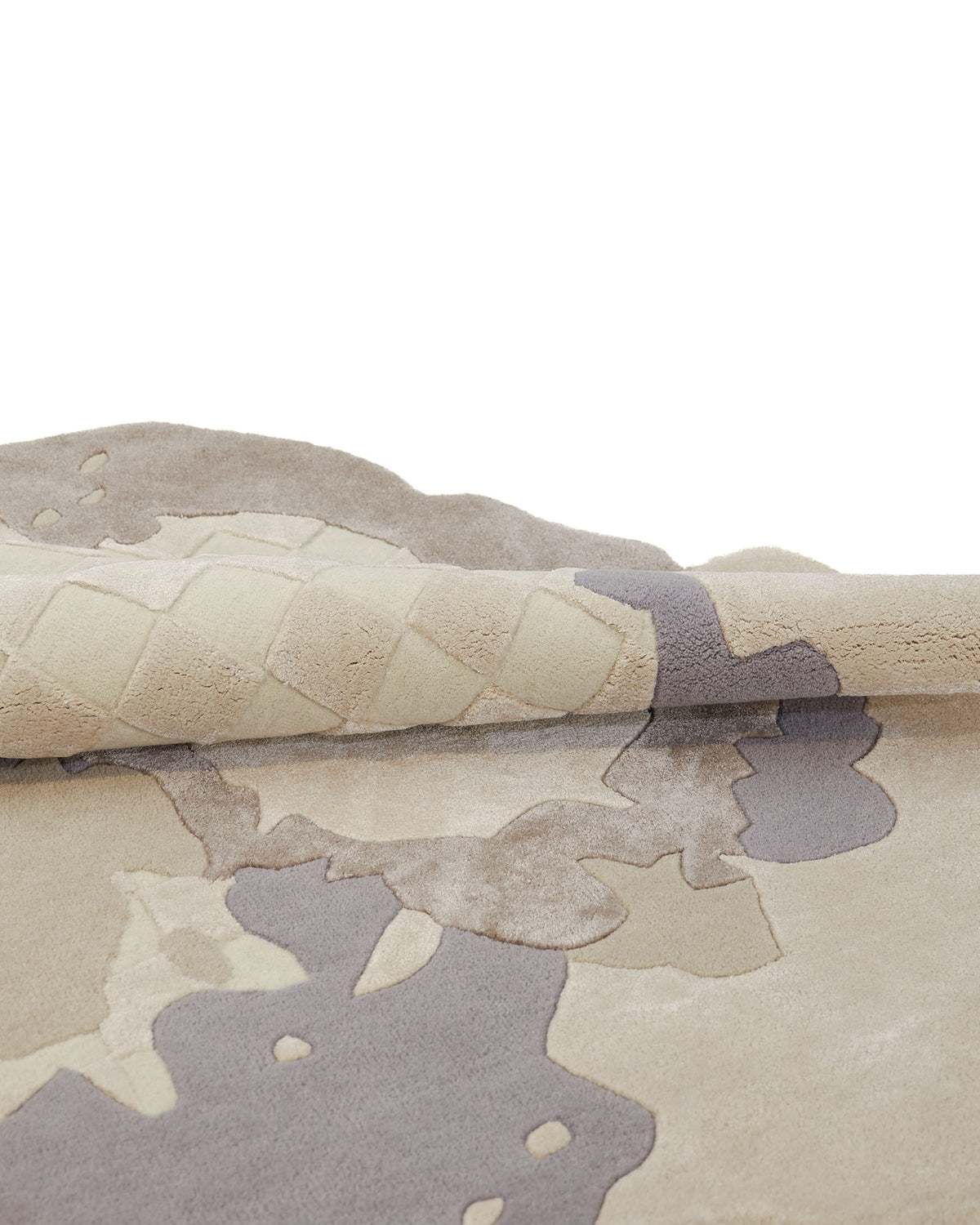 The Abstract Shaped Handmade Area Rug- HTWV 174 (200x300 cm) by RAMSHA HOME, featuring a plush beige and gray pattern, is partially rolled to showcase its dynamic modern design and textured underside.