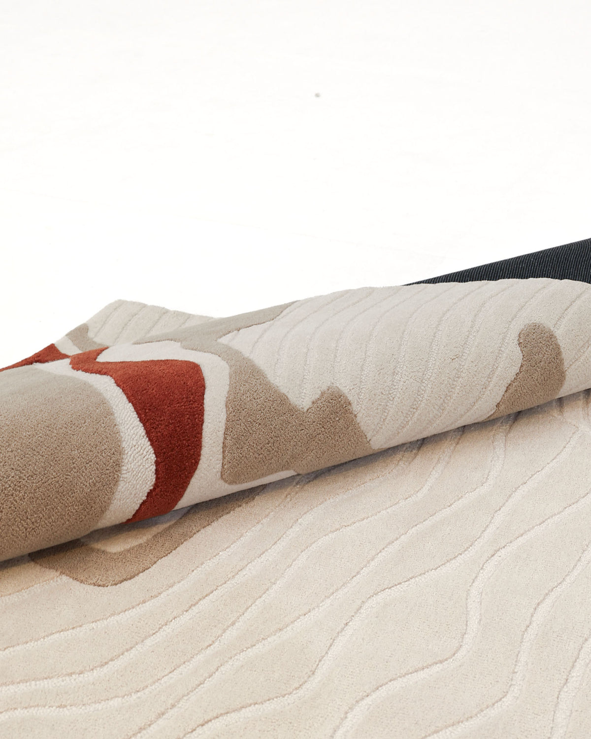 A close-up of the RAMSHA HOME Modern Handmade Carpet 300x400 Multi – HTW-120 showcases its textured, hand-tufted wool construction with beige, cream, tan, and rust-colored patterns. The partially rolled rug reveals its wavy, raised surface and contemporary abstract design.