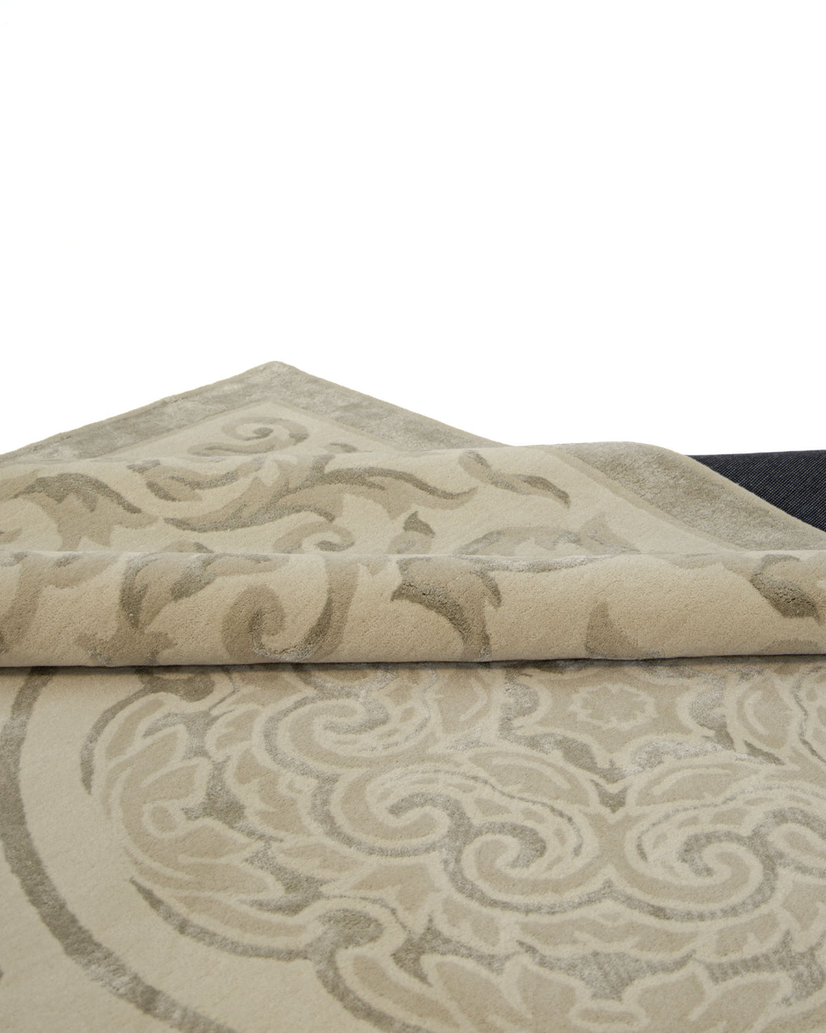 The RAMSHA HOME Amazing Multi Color Modern Floor Rug - HTWV 57 (300x400cm) features an ornate swirling pattern reminiscent of a traditional medallion design, in beige and tan tones. Partly folded against a white background, the rug’s thickness and texture are clearly displayed.
