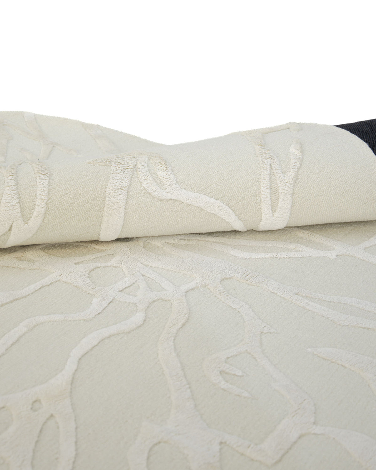 A close-up of the Premium Beige Handmade Carpet HTWV-100 – 200×300 cm by RAMSHA HOME, featuring a modern wool design with a raised, abstract pattern; the carpet is shown partially folded to highlight its texture and thickness.