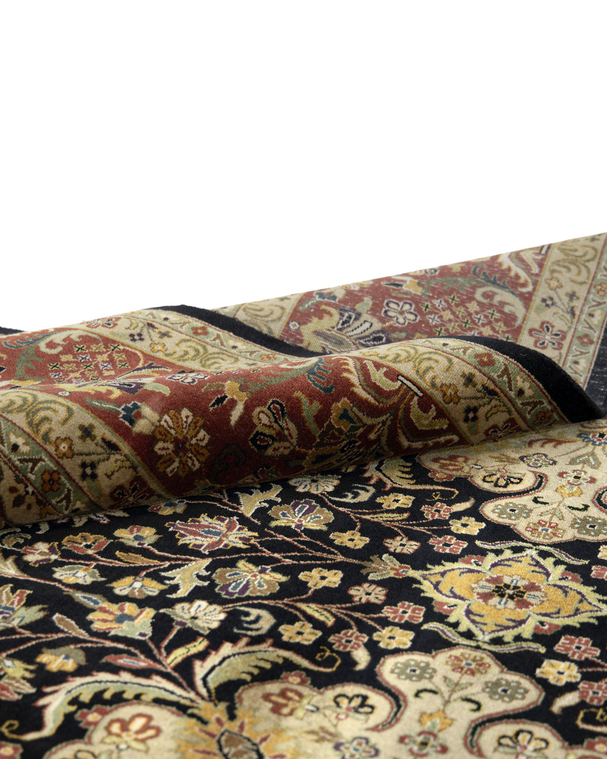 A close-up of the RAMSHA HOME Persian Design Area Rug - HKW-06, showcasing its hand-knotted floral and geometric motifs in black, gold, red, and cream tones, partially folded on a white background.