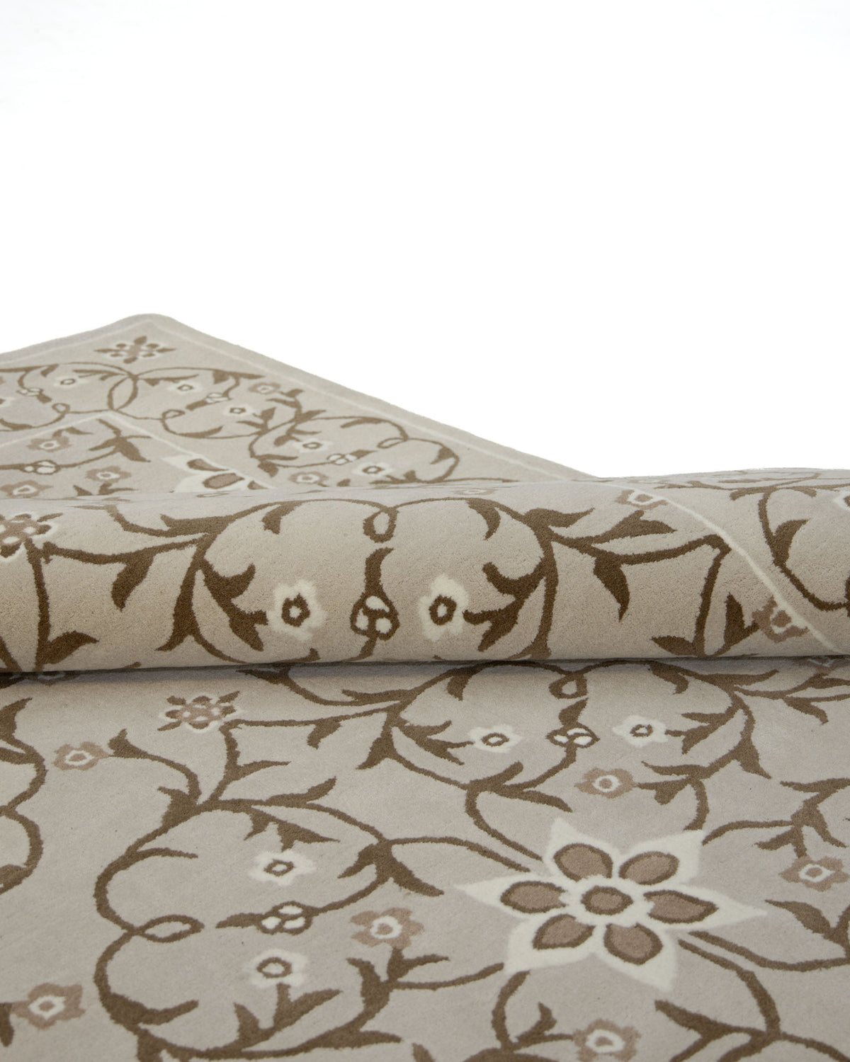 A close-up of the RAMSHA HOME Exquisite Multi Color Decor Handmade Rug - HTW 99 (300x400 CM) showcases its hand-tufted wool construction with intricate beige and brown floral and vine patterns, partially rolled on a white background.