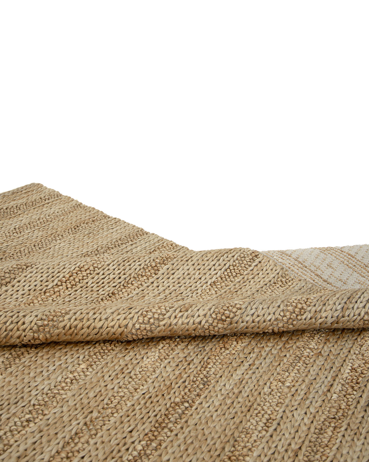 A close-up of the RAMSHA HOME Natural Color Hand Woven Jute Rug SR-043 in beige and tan, featuring a partially folded corner that highlights its natural texture and pattern against a white background.