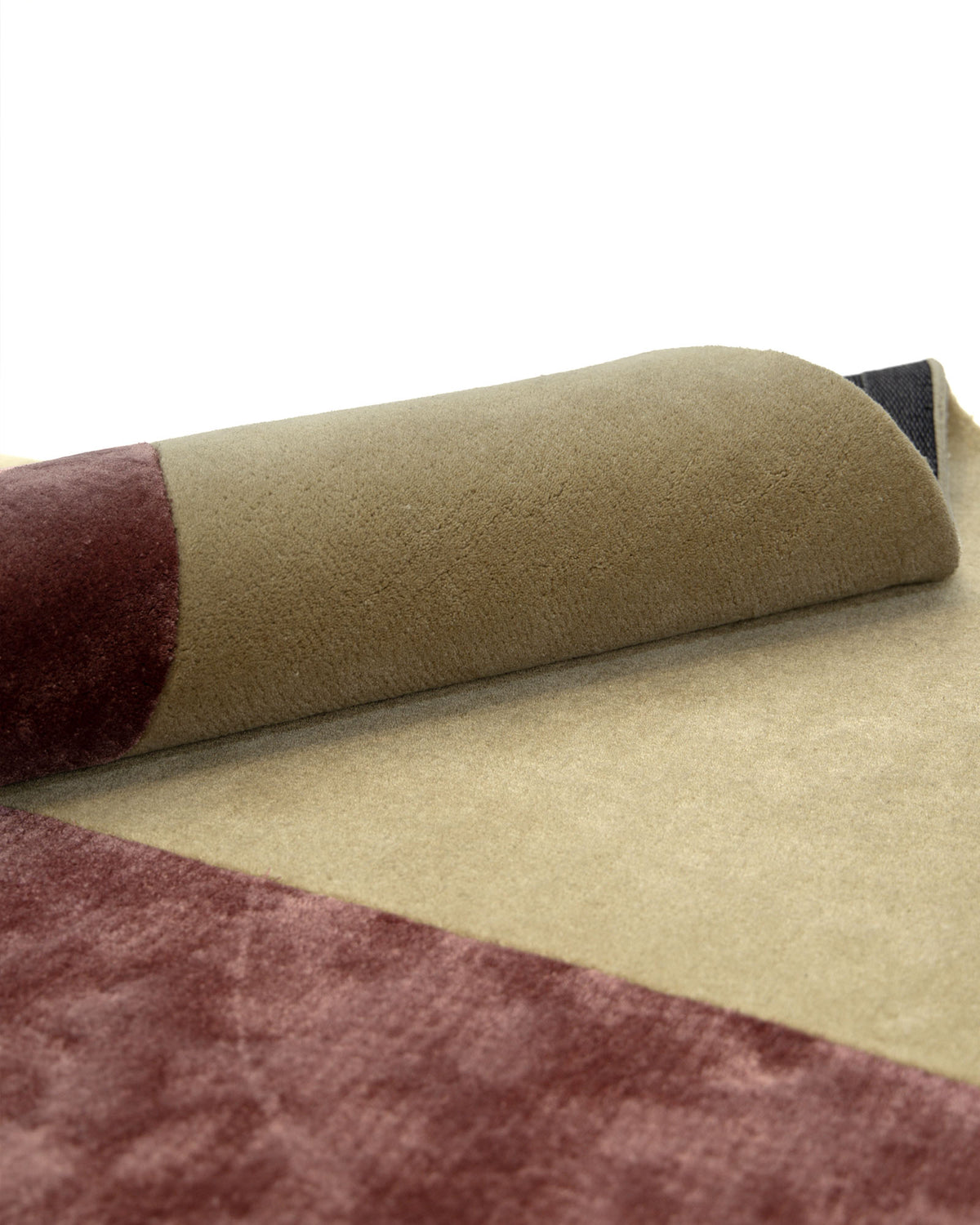 A close-up of the RAMSHA HOME Multi Color Handmade Rug HTWV-20, partially rolled up to display the olive green and maroon color blocks and highlighting the thick, textured wool viscose material.