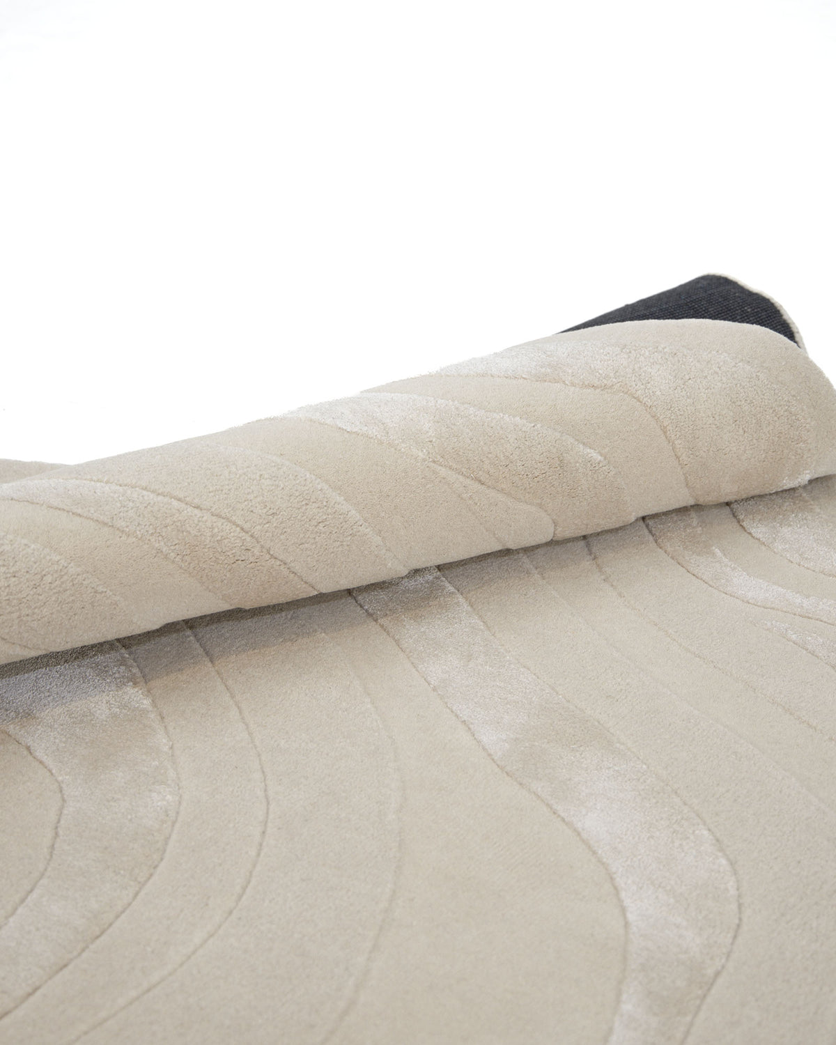 A close-up of the RAMSHA HOME Handmade Beige Organic Shape Rug with Wave Pattern (200x300 cm – HTWV 210), partially rolled up on a white background.