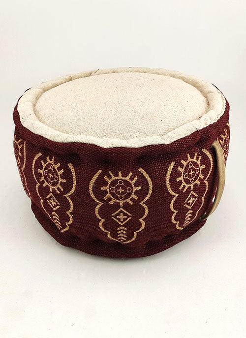 The RAMSHA HOME Red Color Jute Pouf With Handle PF-059 features a round design with gold patterns, a beige top, and a metal side handle—ideal for modern décor and displayed on a plain white background.