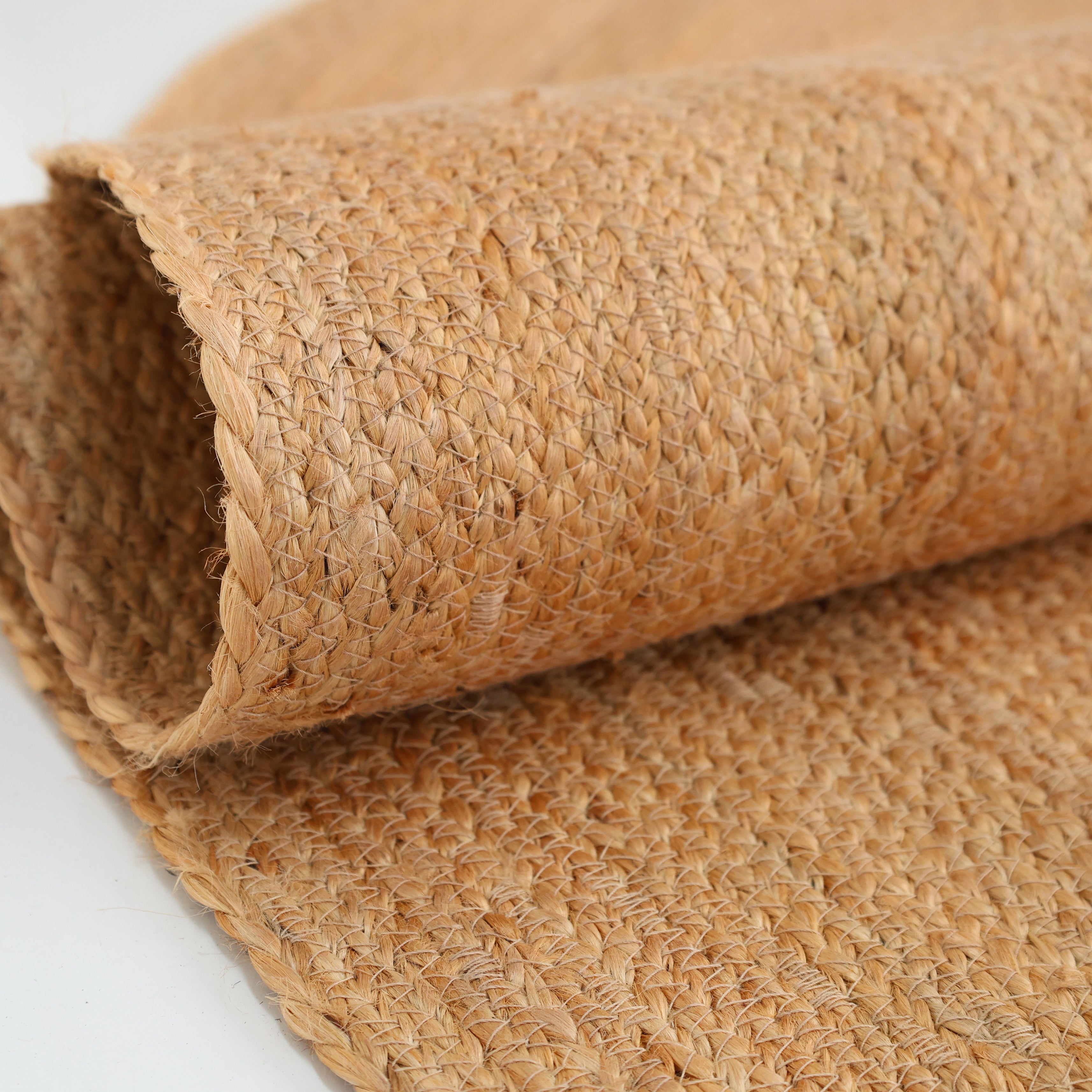 A close-up of the RAMSHA HOME Handmade Natural Color Oval Shape Braided Rug - BR 036, displaying its textured pattern and natural tan hue—an elegant jute fiber piece for any space.