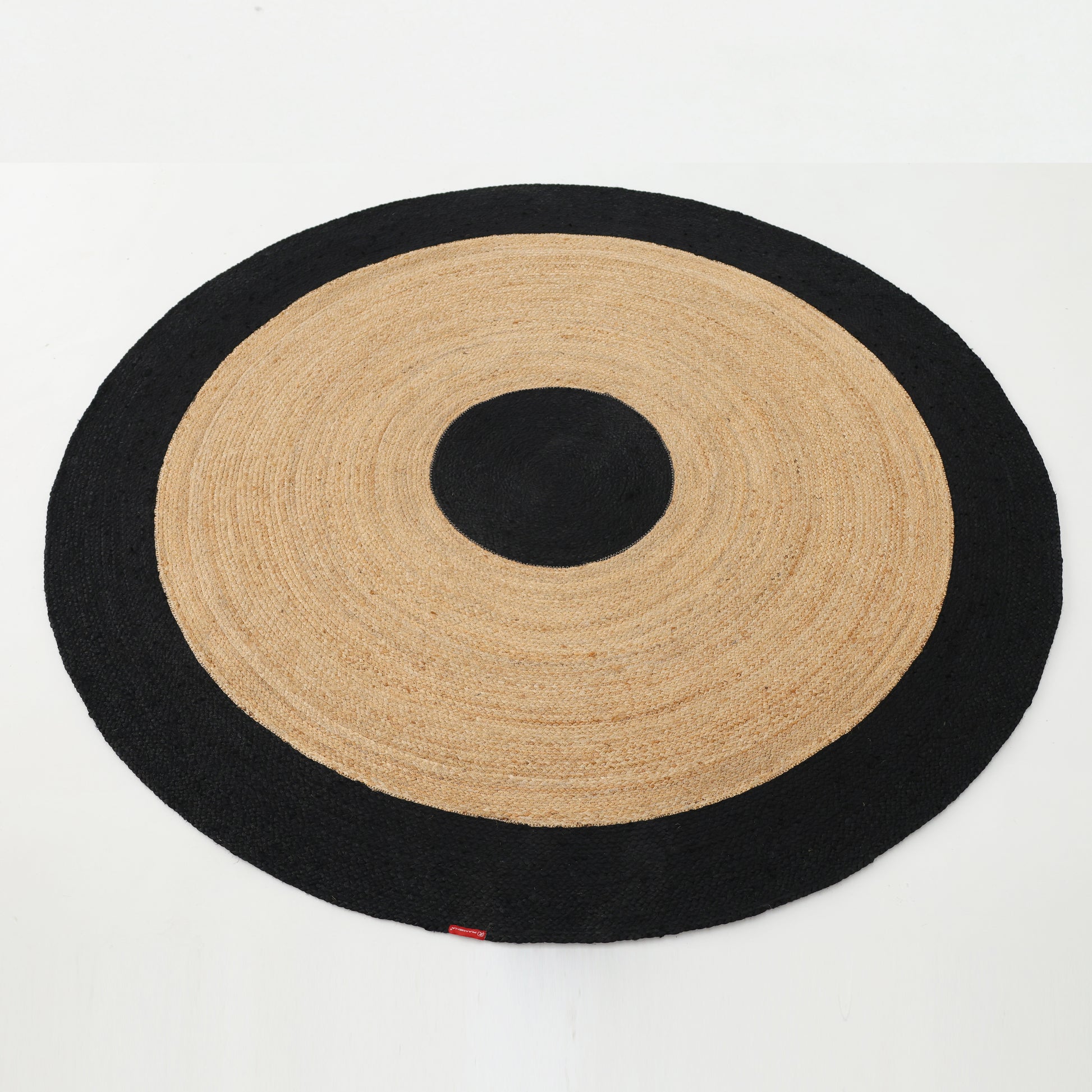 The RAMSHA HOME Braided Rug Jute carpet BR-003 showcases a round black and natural beige design with bold circular accents and a thick black border, creating a striking contrast on a white floor.