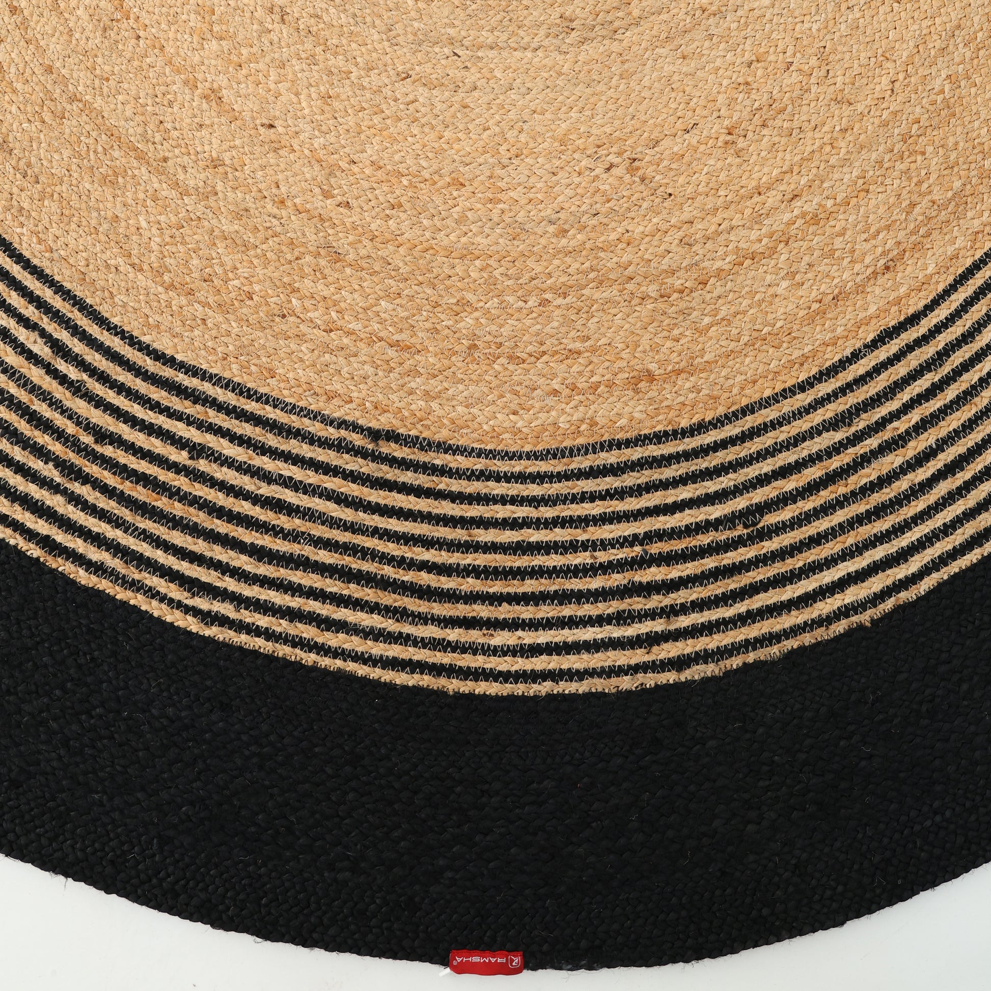 The Luxurious Handmade Braided Jute Round Rug - BR 028 by RAMSHA HOME features concentric circles with a natural tan center, alternating tan and black stripes, and a solid black border.