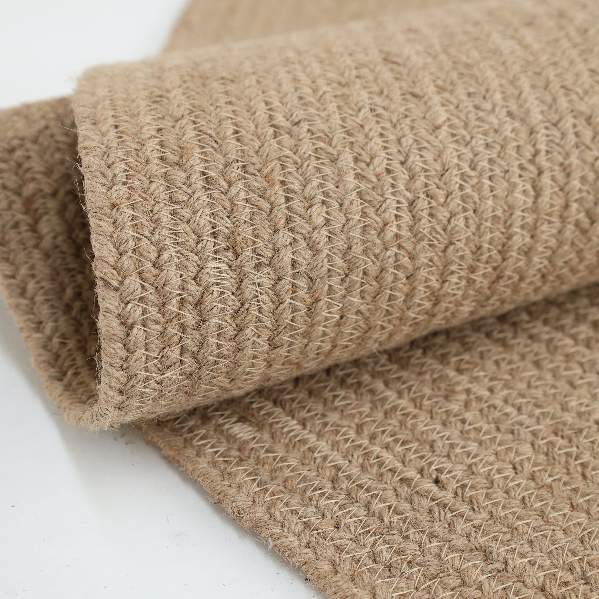 A close-up of the RAMSHA HOME Stunning Handmade Jute Indoor & Outdoor Round Braided Rug - BR 014, highlighting its beige textured pattern and thick, sturdy natural fiber threads.